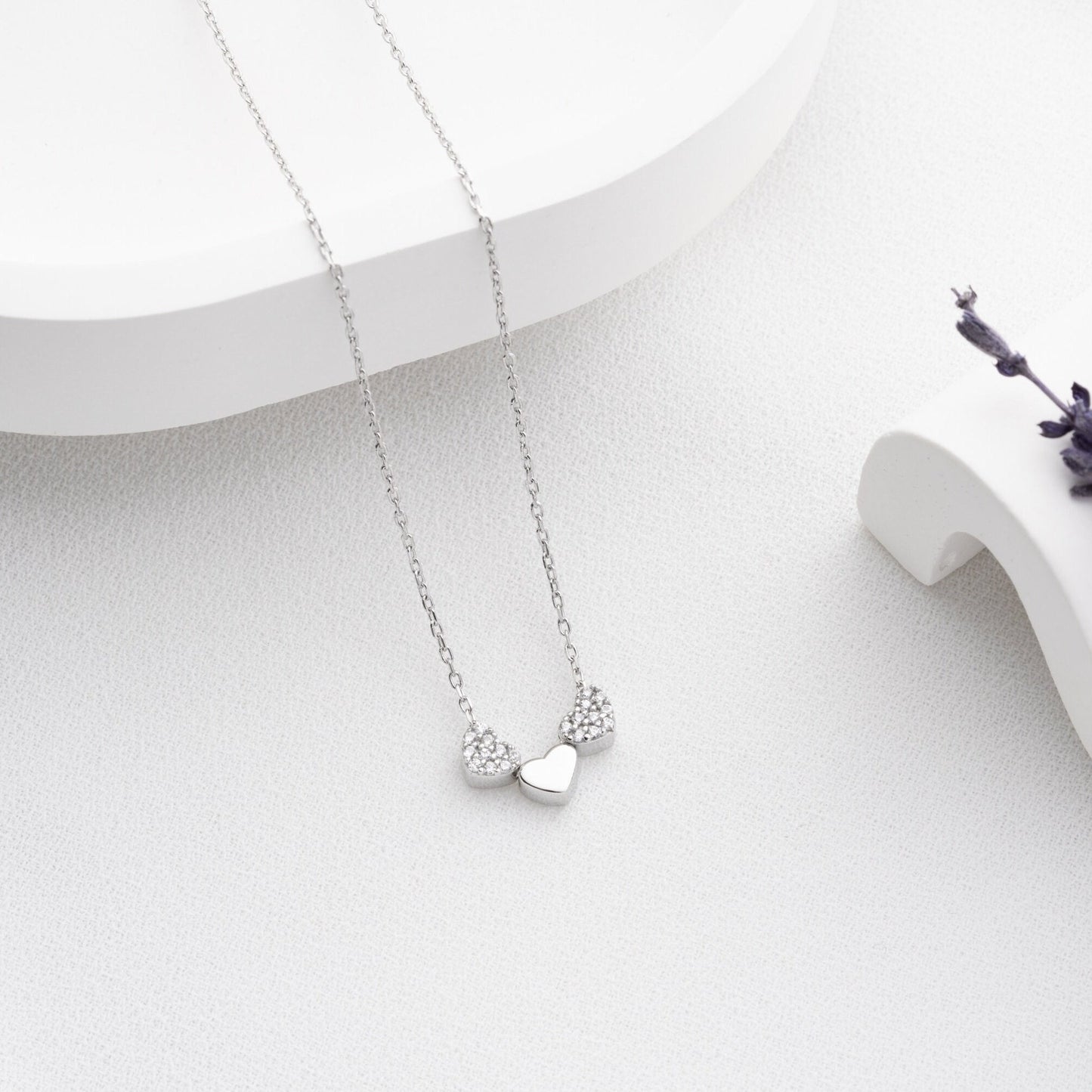 An exquisite silver necklace featuring three interlocking hearts, each heart intricately detailed with sparkling zircon stones, creating a luxurious and romantic piece perfect for gifting on special occasions or expressing love and affection.