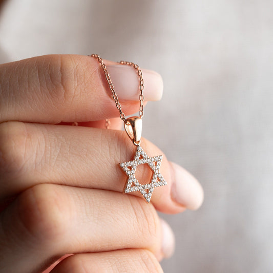 Close-up of a sparkling zircon-embellished Star of David pendant made of 925 sterling silver against a soft white background.