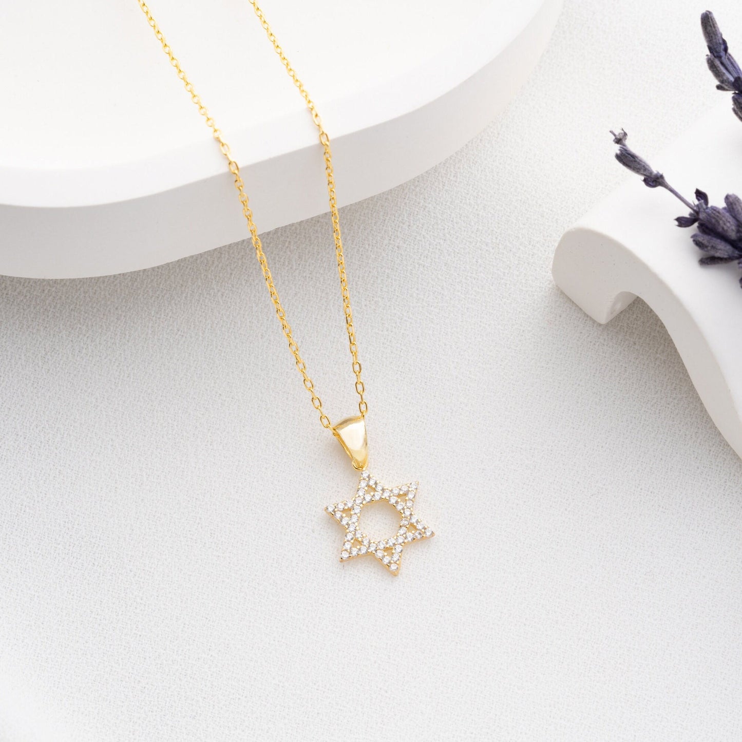 Close-up of a sparkling zircon-embellished Star of David pendant made of 925 sterling silver against a soft white background.