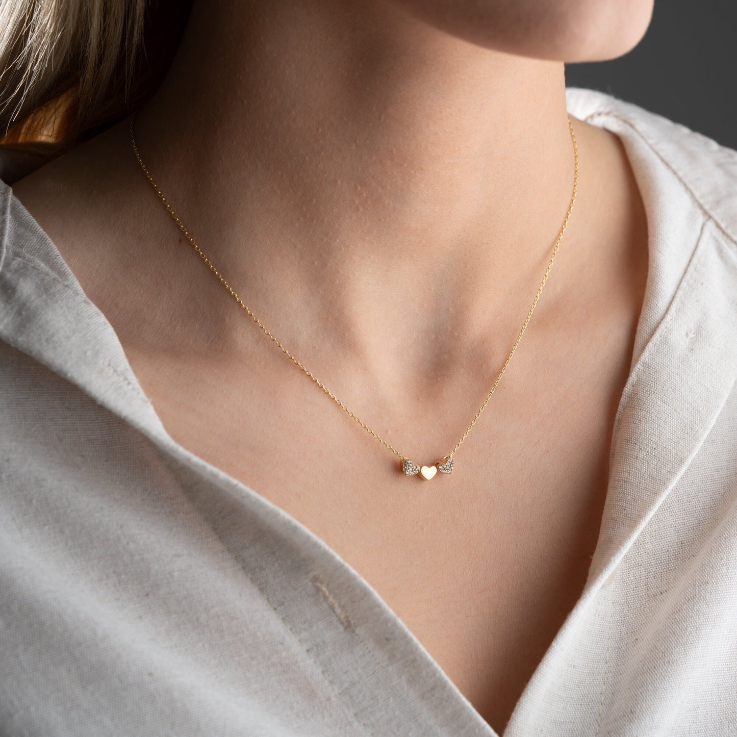 An exquisite silver necklace featuring three interlocking hearts, each heart intricately detailed with sparkling zircon stones, creating a luxurious and romantic piece perfect for gifting on special occasions or expressing love and affection.