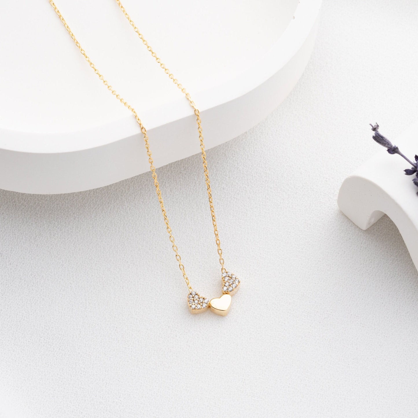 An exquisite silver necklace featuring three interlocking hearts, each heart intricately detailed with sparkling zircon stones, creating a luxurious and romantic piece perfect for gifting on special occasions or expressing love and affection.