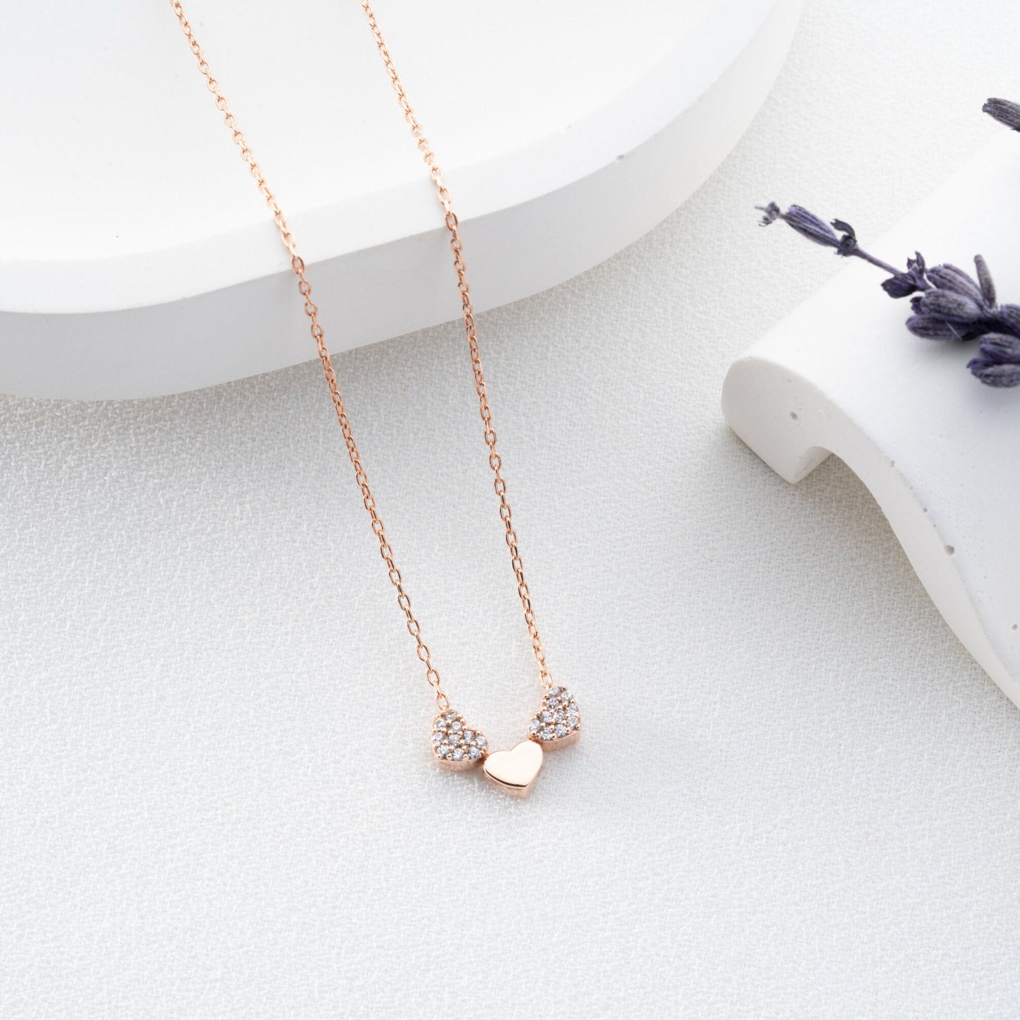An exquisite silver necklace featuring three interlocking hearts, each heart intricately detailed with sparkling zircon stones, creating a luxurious and romantic piece perfect for gifting on special occasions or expressing love and affection.