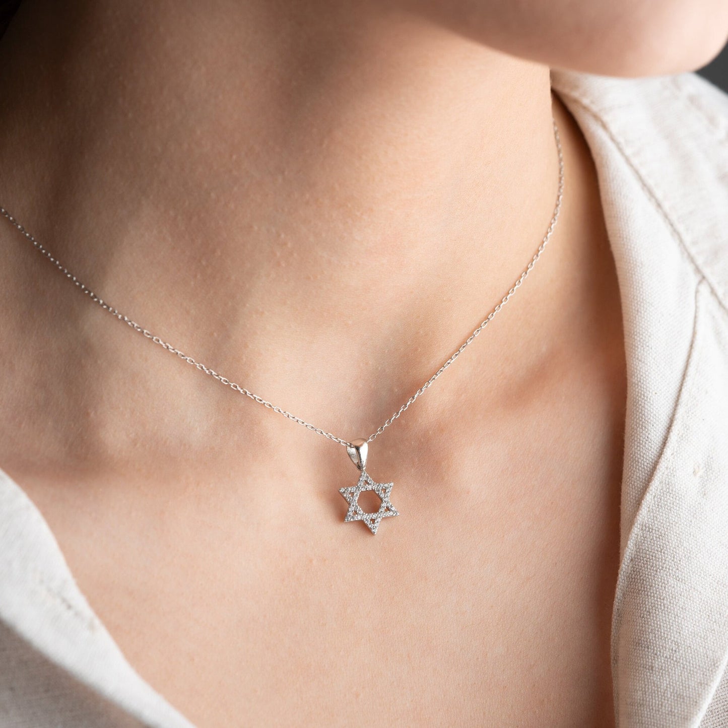 Close-up of a sparkling zircon-embellished Star of David pendant made of 925 sterling silver against a soft white background.
