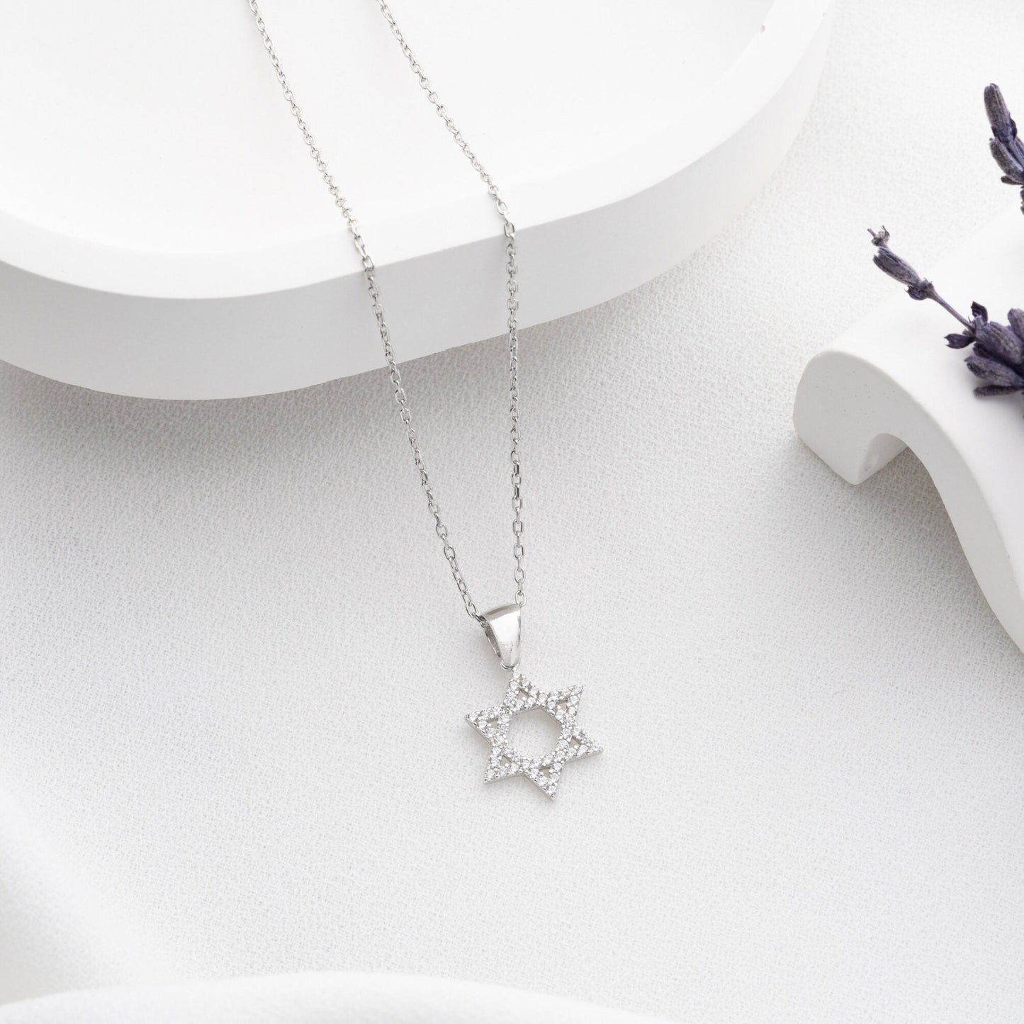 Close-up of a sparkling zircon-embellished Star of David pendant made of 925 sterling silver against a soft white background.