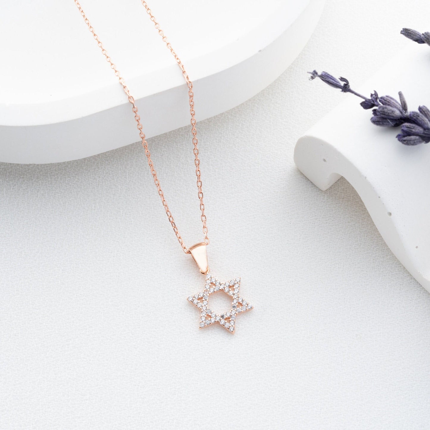 Close-up of a sparkling zircon-embellished Star of David pendant made of 925 sterling silver against a soft white background.