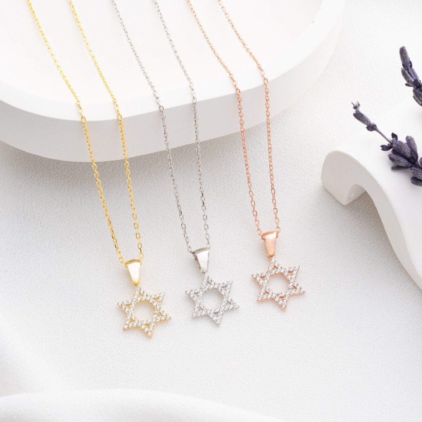 Close-up of a sparkling zircon-embellished Star of David pendant made of 925 sterling silver against a soft white background.