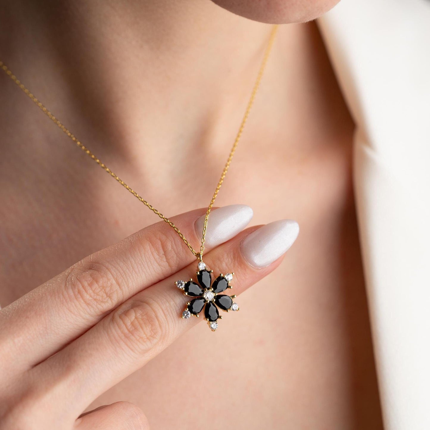 Elegant black flower necklace with genuine zircon stones, available in 925 sterling silver and 14K gold plated options, displayed on a white satin background.