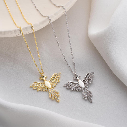 Elegant bird-shaped necklace with cubic zirconia stones, available in 925 sterling silver and 14K gold plated options, displayed on a white satin background.