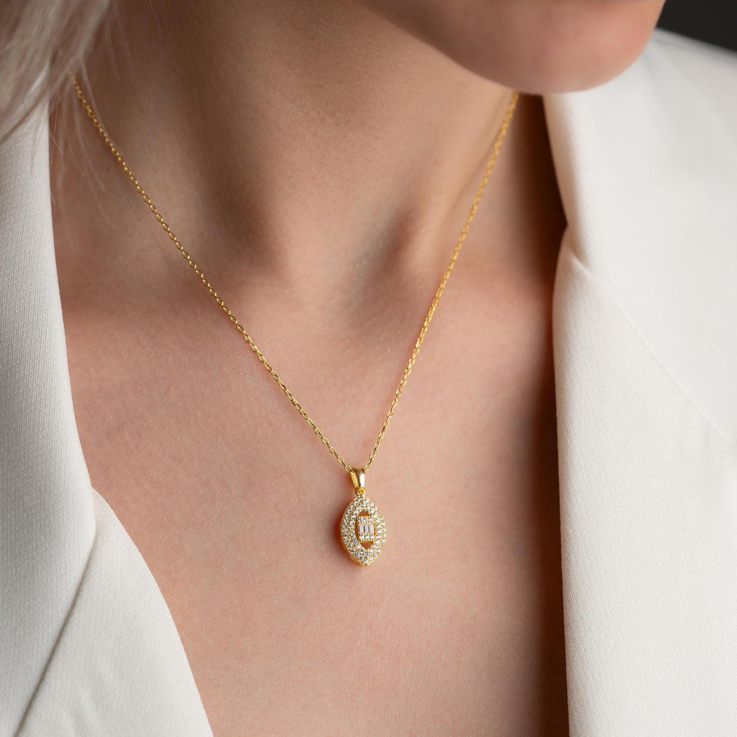 Elegant oval pendant necklace with cubic zirconia stones, available in 925 sterling silver and 14K gold plated options, displayed on a white satin background.