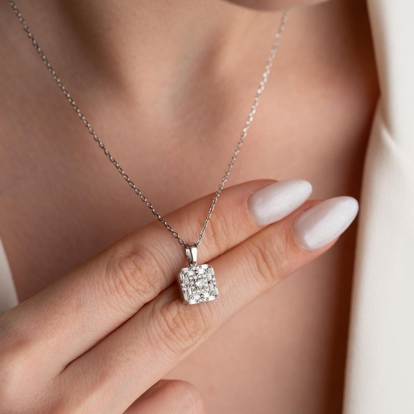 Square pendant necklace with cubic zirconia stones, available in 925 sterling silver and 14K gold plated options, displayed on a white satin background.