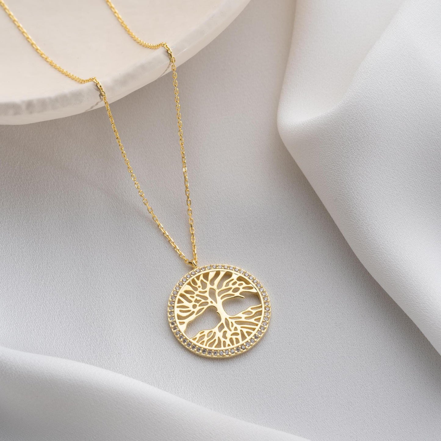 Tree of Life necklace with cubic zirconia stones, available in 925 sterling silver and 14K gold plated options, displayed on a white satin background.