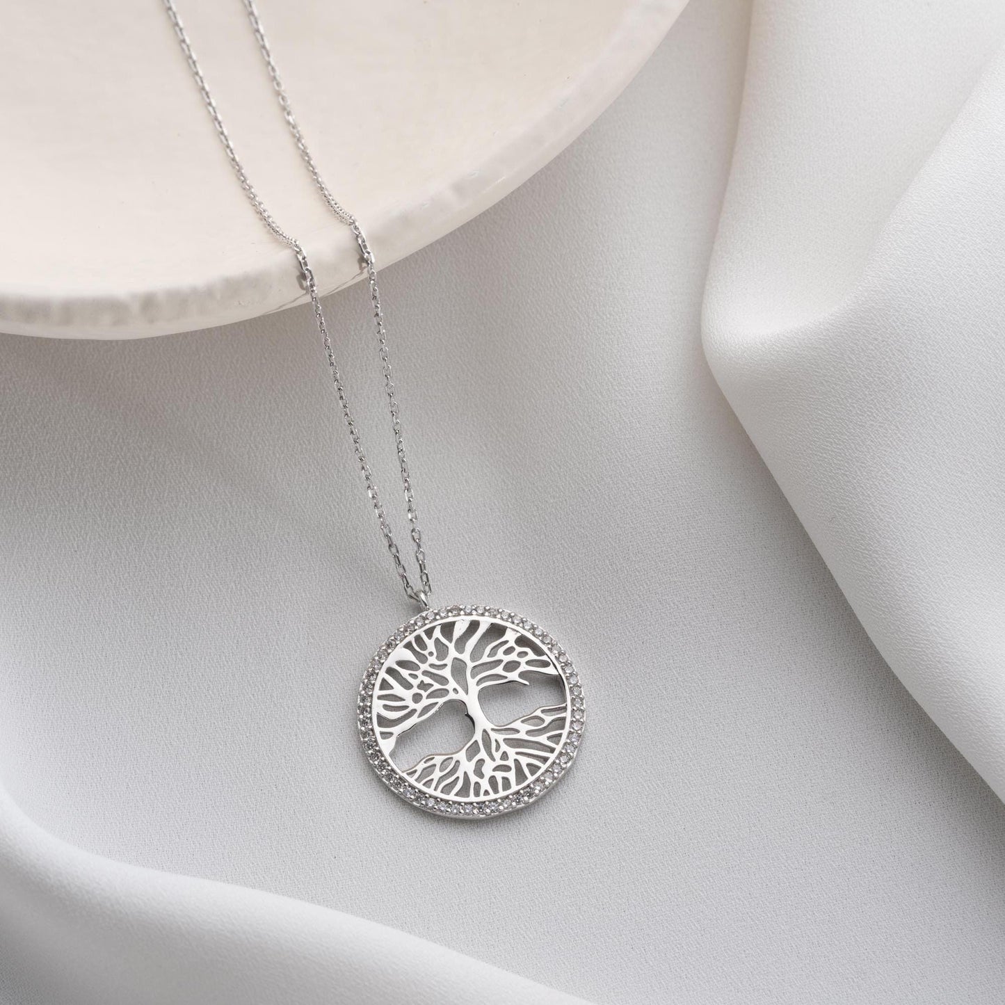 Tree of Life necklace with cubic zirconia stones, available in 925 sterling silver and 14K gold plated options, displayed on a white satin background.
