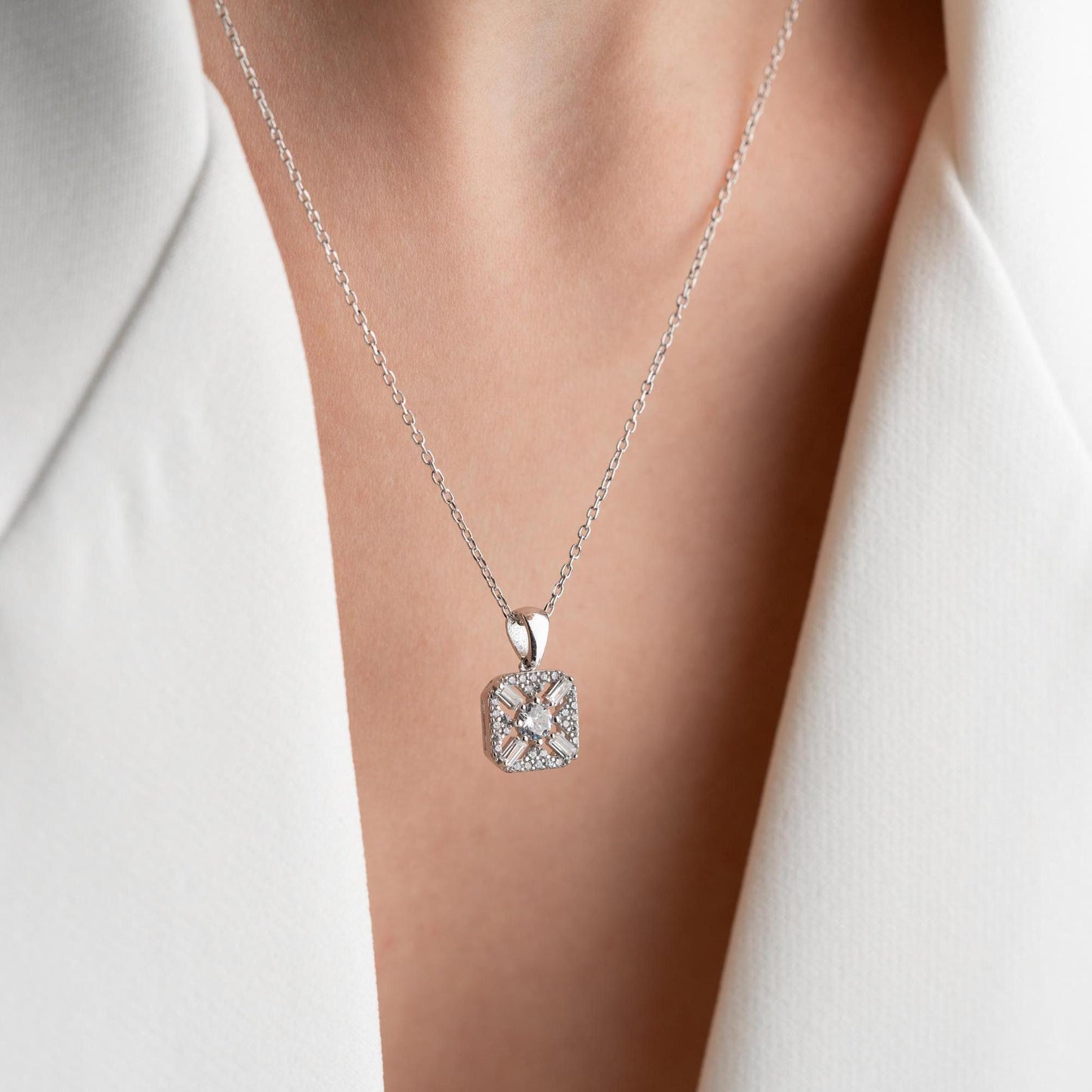 Square pendant necklace with cubic zirconia stones, available in 925 sterling silver and 14K gold plated options, displayed on a white satin background