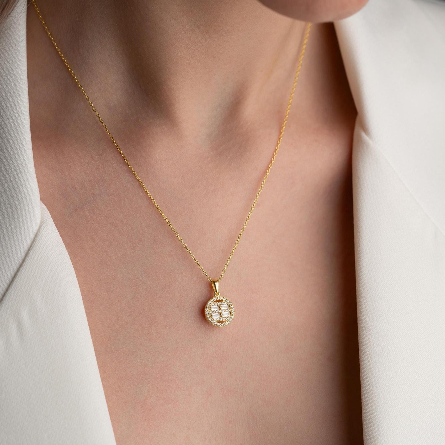 Round pendant necklace with cubic zirconia stones, available in 925 sterling silver and 14K gold plated options, displayed on a white satin background.