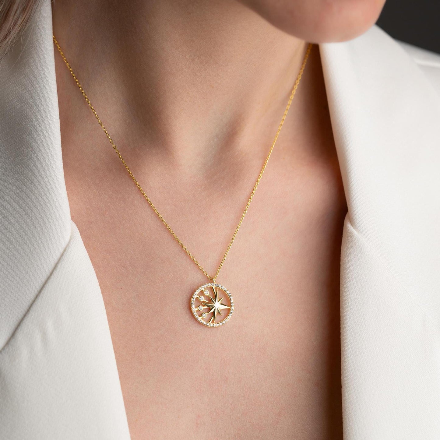North Star pendant necklace with cubic zirconia stones, available in 925 sterling silver and 14K gold plated options, displayed on a white satin background