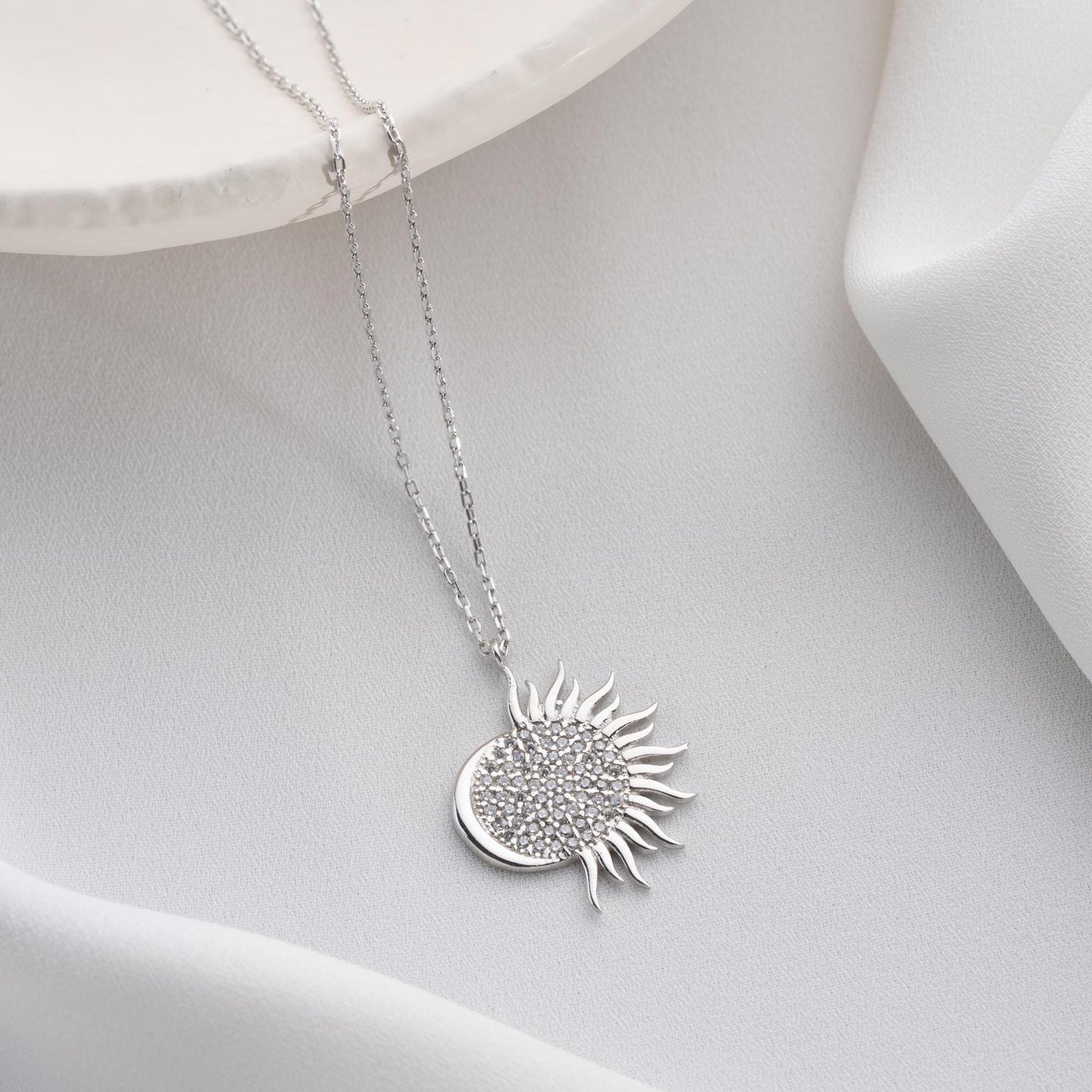 Sun pendant necklace with cubic zirconia stones, available in 925 sterling silver and 14K gold plated options, displayed on a white satin background