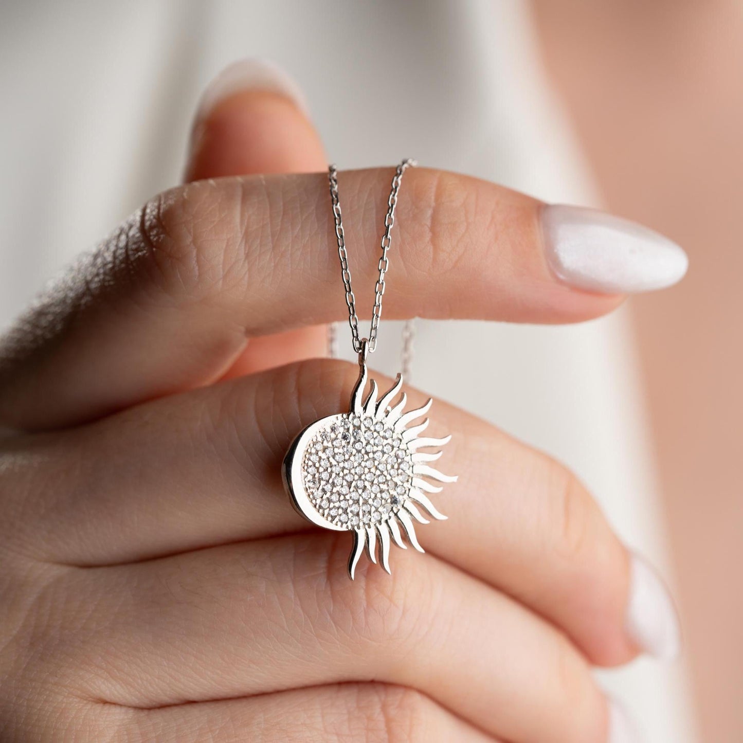 Sun pendant necklace with cubic zirconia stones, available in 925 sterling silver and 14K gold plated options, displayed on a white satin background