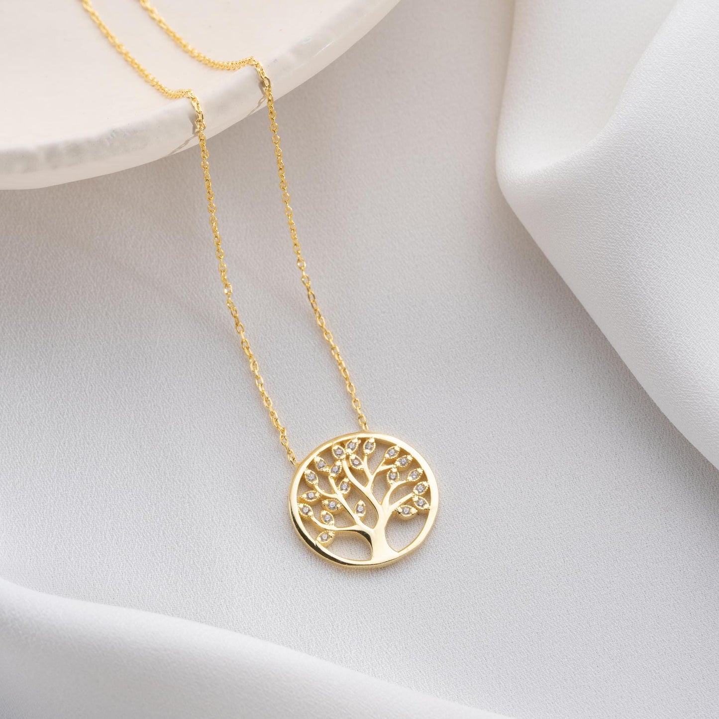 Tree of Life pendant necklace with cubic zirconia stones, available in 925 sterling silver and 14K gold plated options, displayed on a white satin background