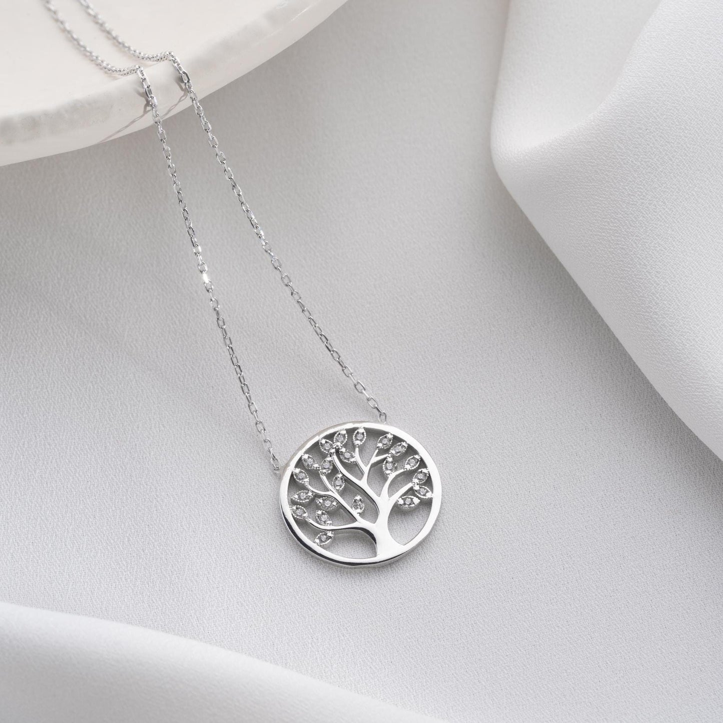 Tree of Life pendant necklace with cubic zirconia stones, available in 925 sterling silver and 14K gold plated options, displayed on a white satin background