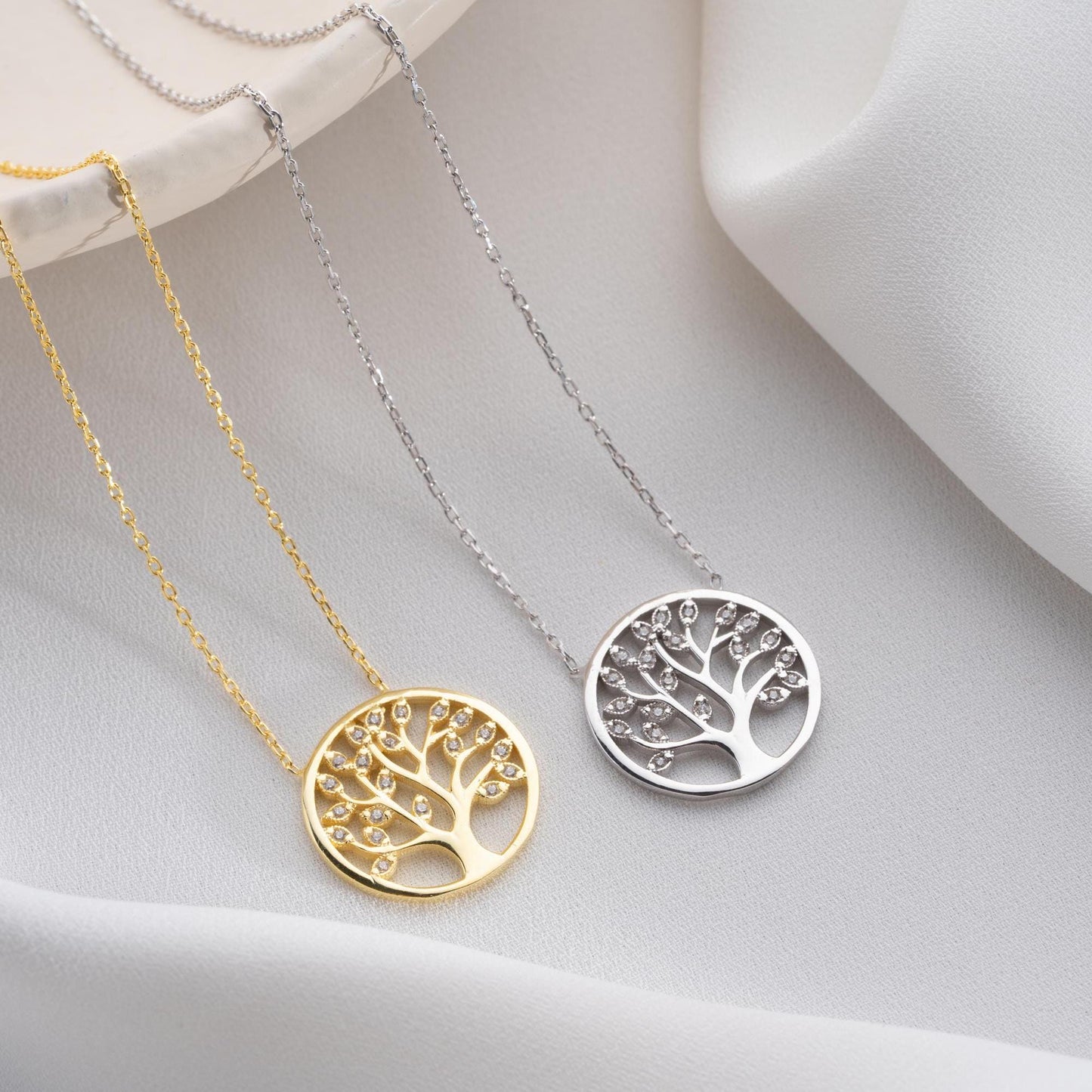 Tree of Life pendant necklace with cubic zirconia stones, available in 925 sterling silver and 14K gold plated options, displayed on a white satin background