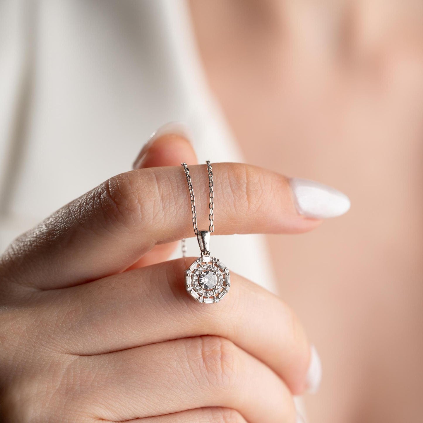 Halo pendant necklace with cubic zirconia stones, available in 925 sterling silver and 14K gold plated options, displayed on a white satin background.