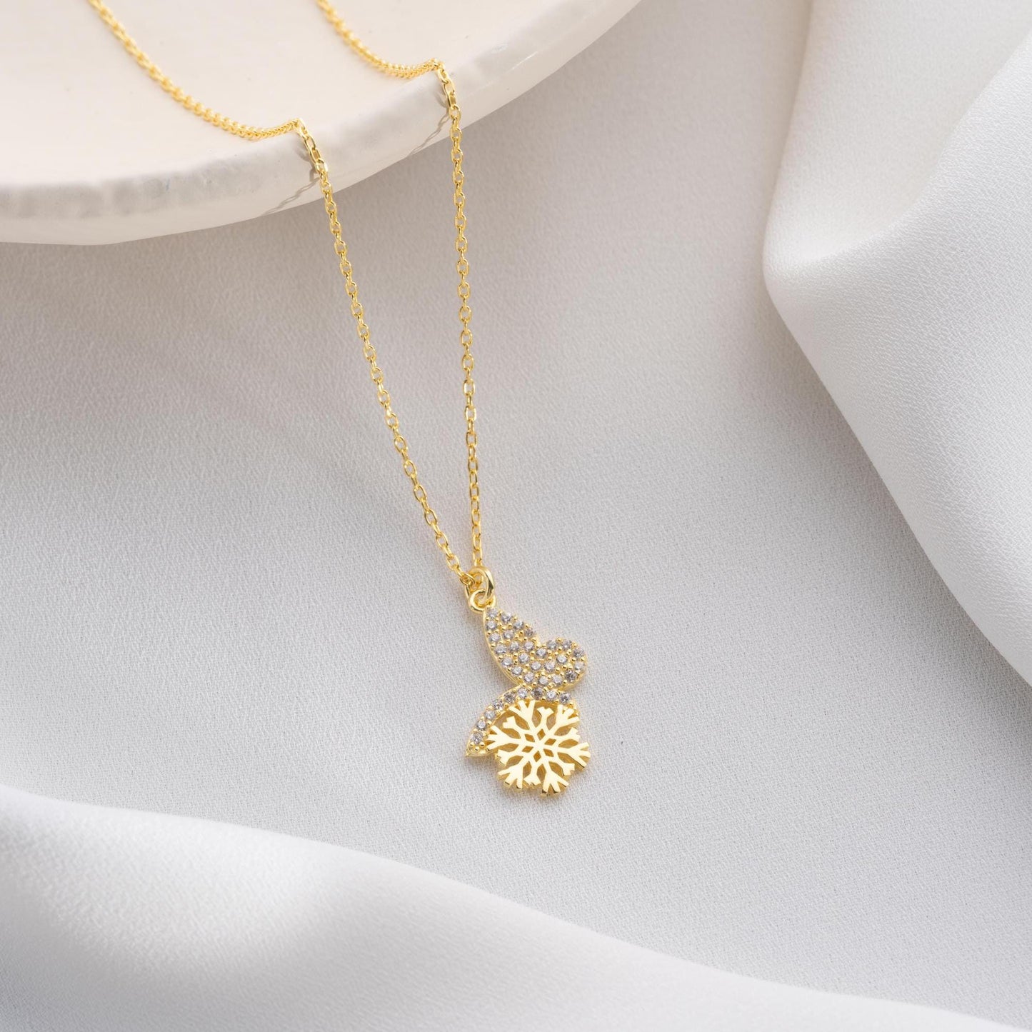 Snowflake heart necklace with cubic zirconia stones, available in 925 sterling silver and 14K gold plated options, displayed on a white satin background