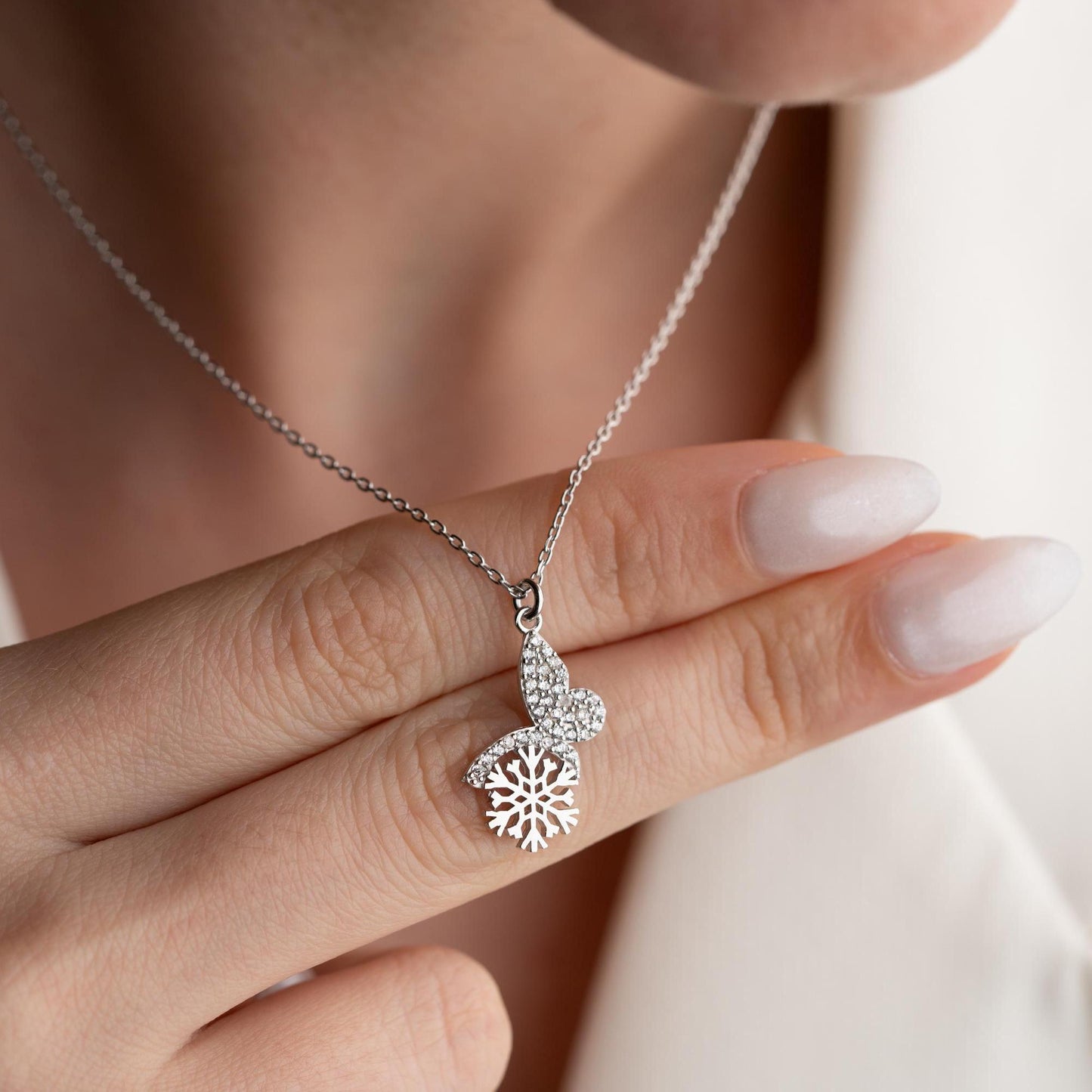 Snowflake heart necklace with cubic zirconia stones, available in 925 sterling silver and 14K gold plated options, displayed on a white satin background