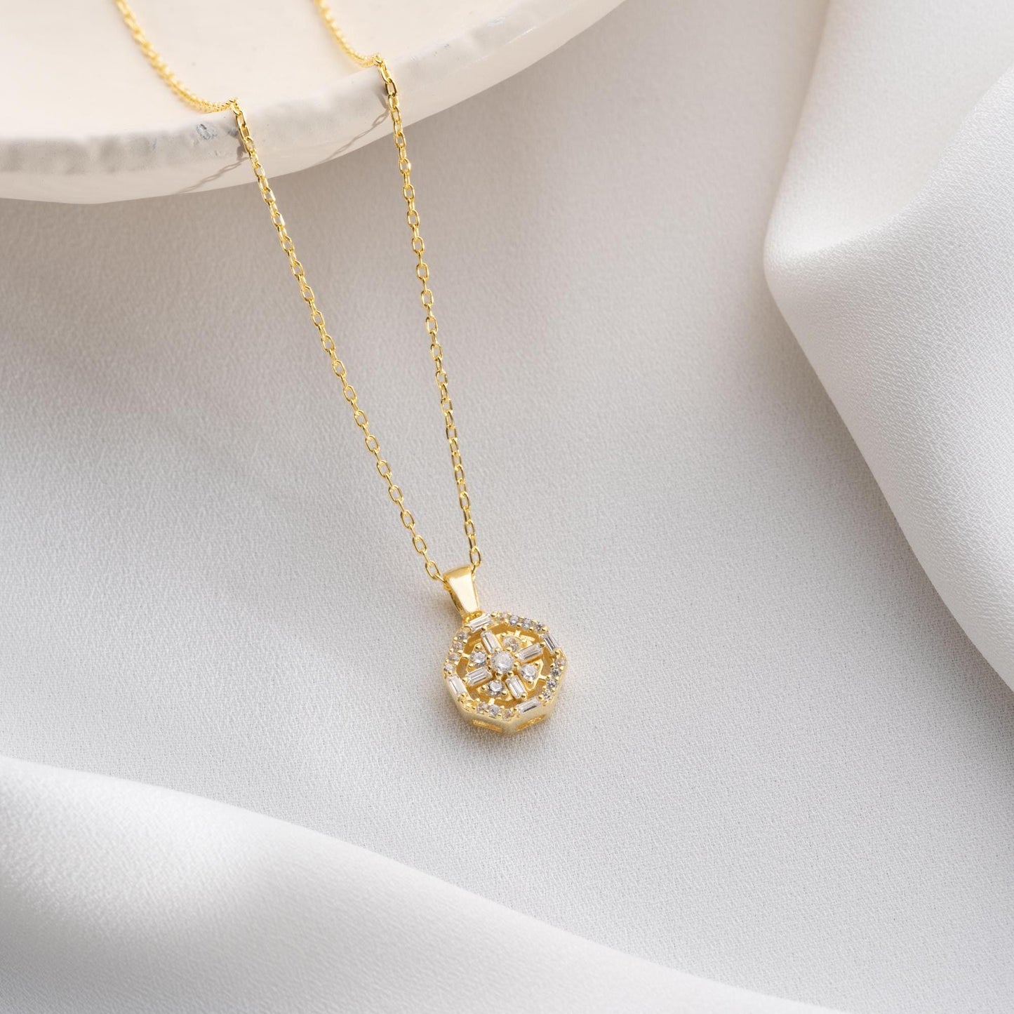 Octagon pendant necklace with cubic zirconia stones, available in 925 sterling silver and 14K gold plated options, displayed on a white satin background