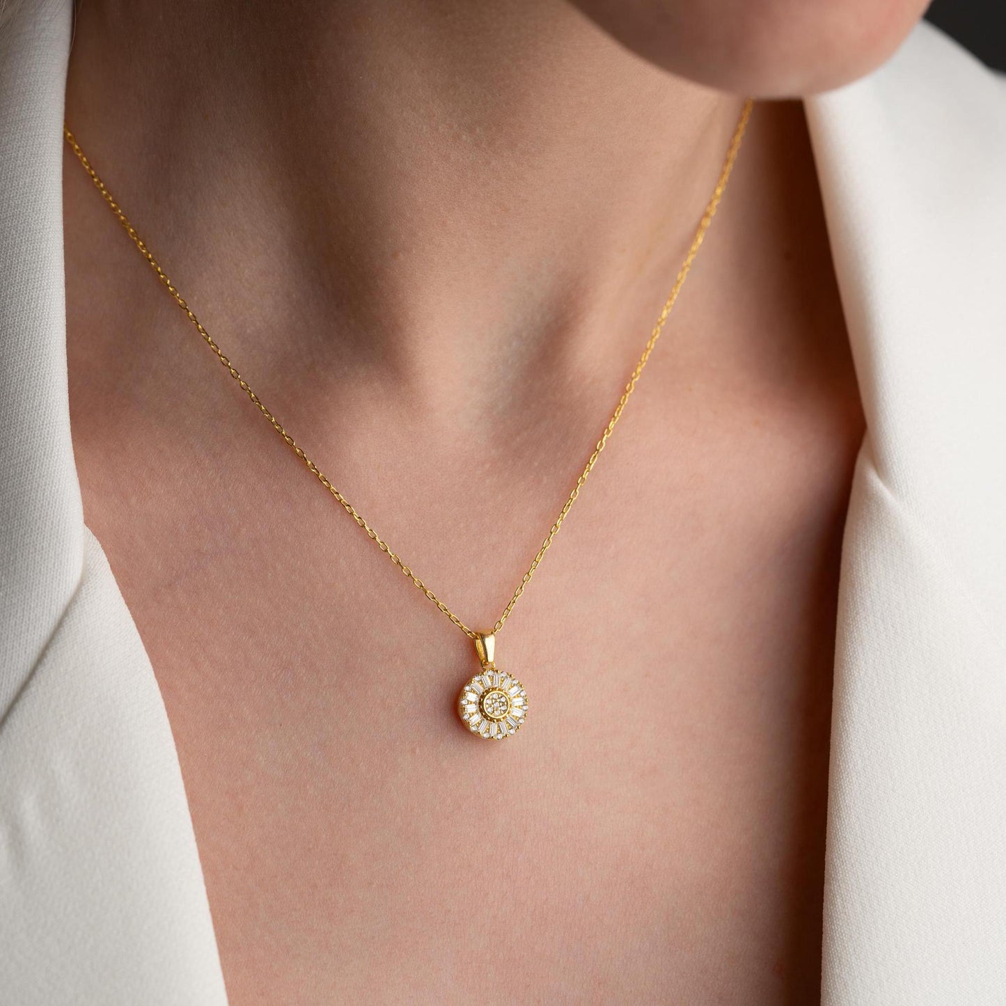 Sunburst pendant necklace with cubic zirconia, available in 925 sterling silver and 14K gold plated options, displayed on a soft satin background