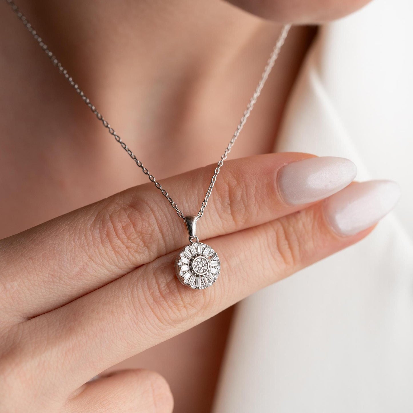 Sunburst pendant necklace with cubic zirconia, available in 925 sterling silver and 14K gold plated options, displayed on a soft satin background