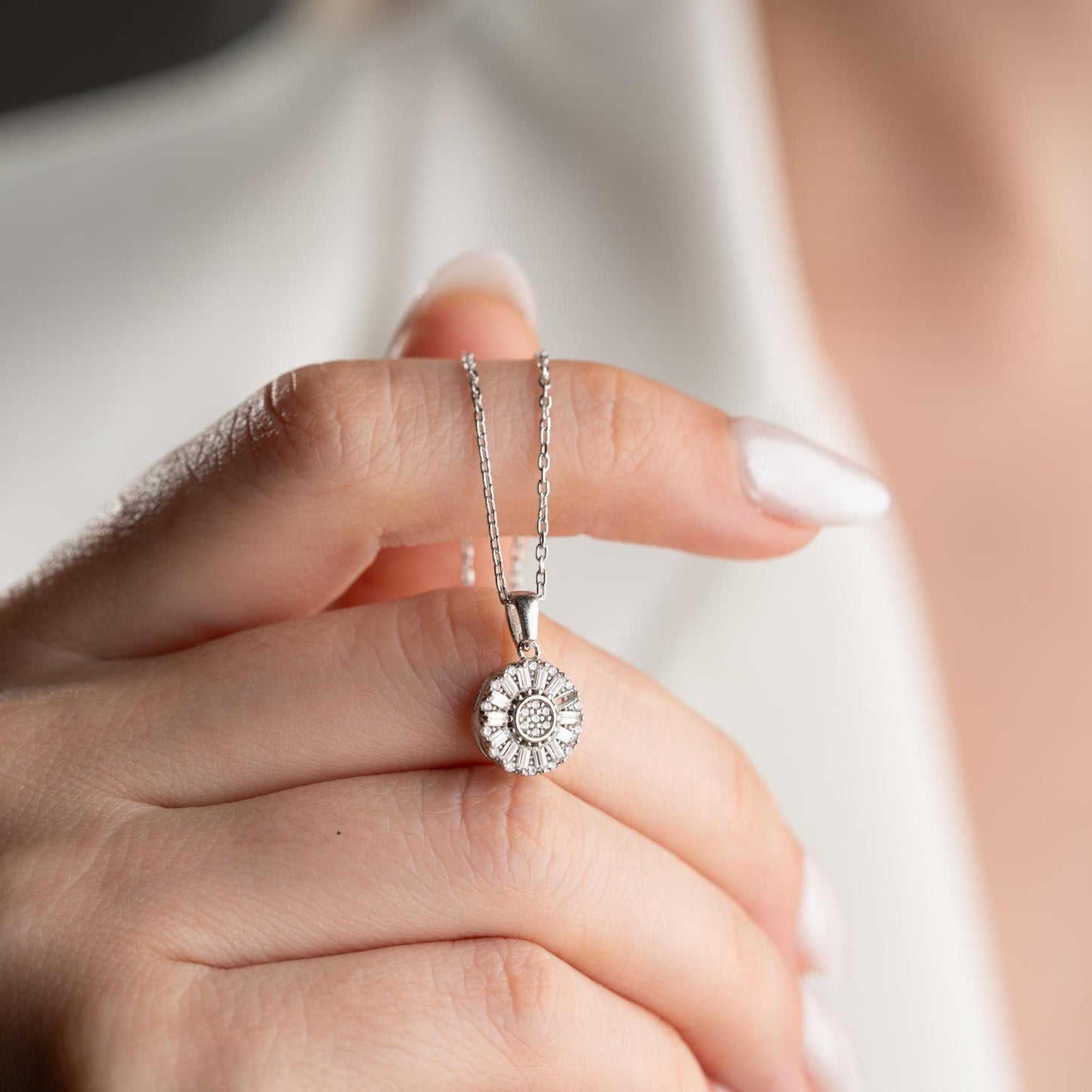 Sunburst pendant necklace with cubic zirconia, available in 925 sterling silver and 14K gold plated options, displayed on a soft satin background