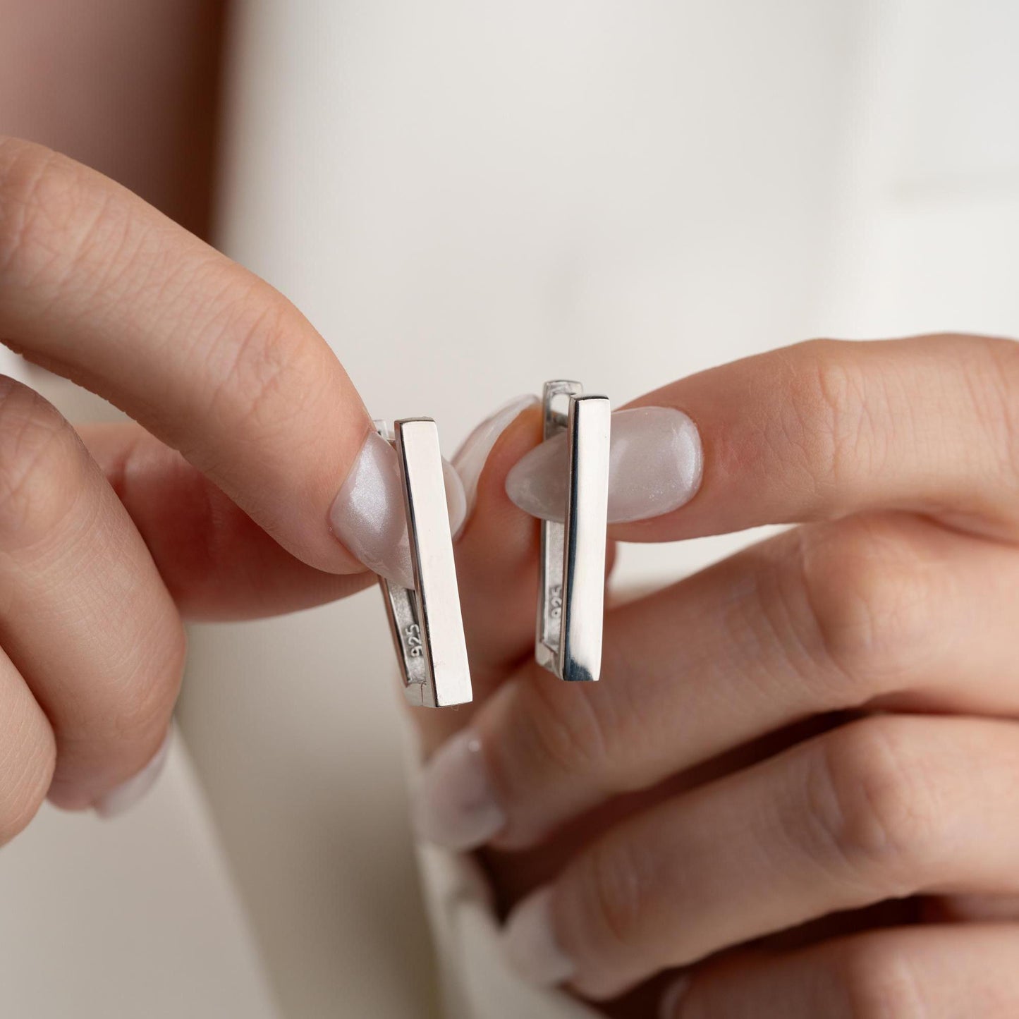 Minimalist rectangular hoop earrings crafted from 925 sterling silver with a 14K gold plated option, displayed on a marble surface.