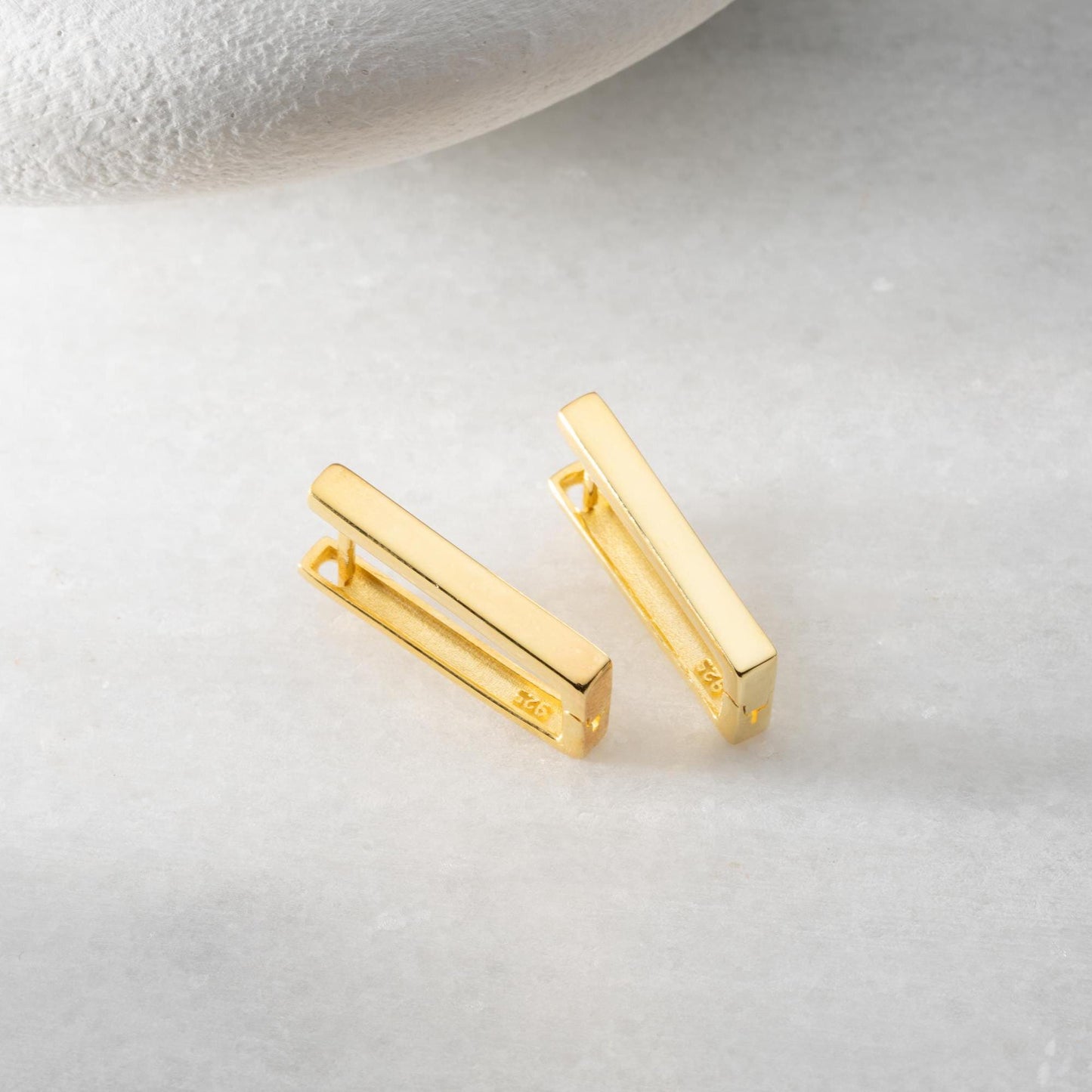 Minimalist rectangular hoop earrings crafted from 925 sterling silver with a 14K gold plated option, displayed on a marble surface.