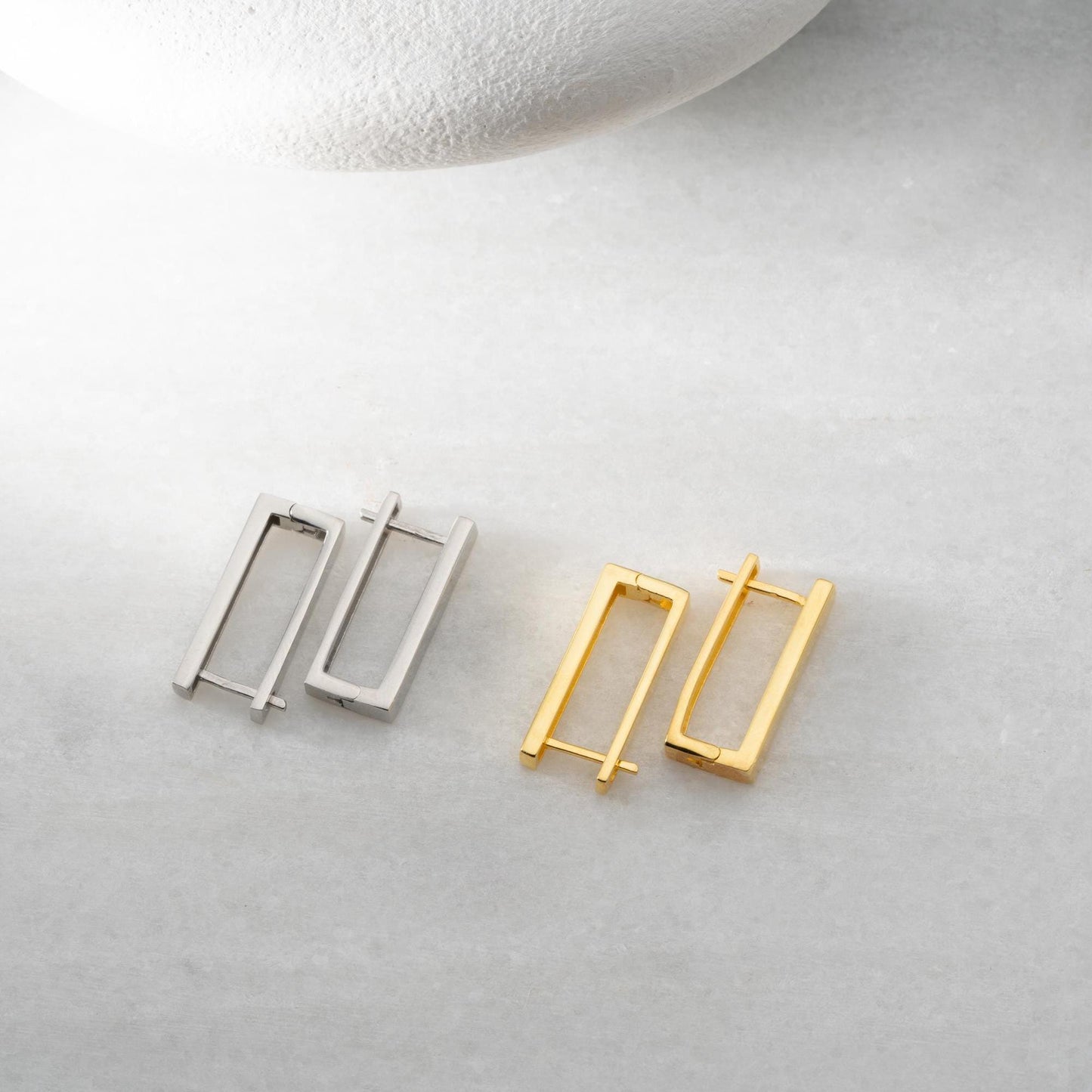 Minimalist rectangular hoop earrings crafted from 925 sterling silver with a 14K gold plated option, displayed on a marble surface.
