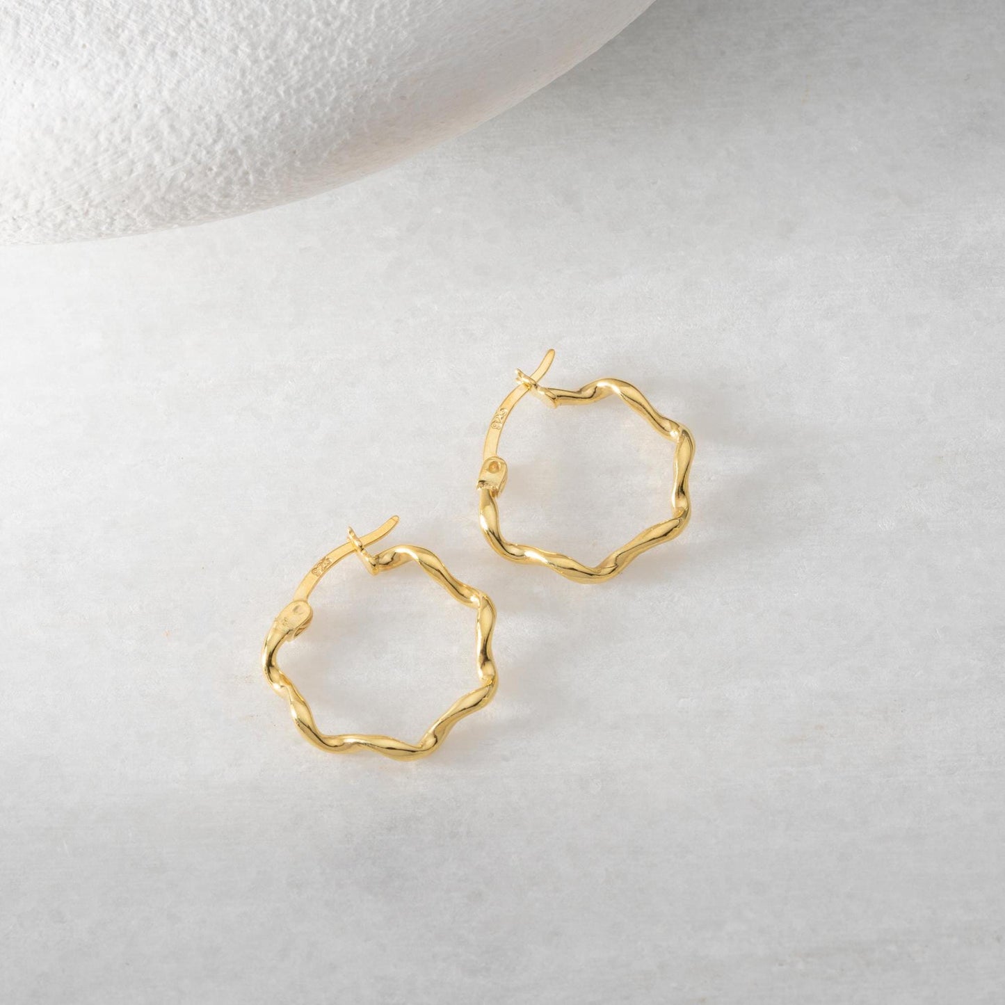 Wave hoop earrings crafted from 925 sterling silver with 14K gold plating option, displayed on a marble background.