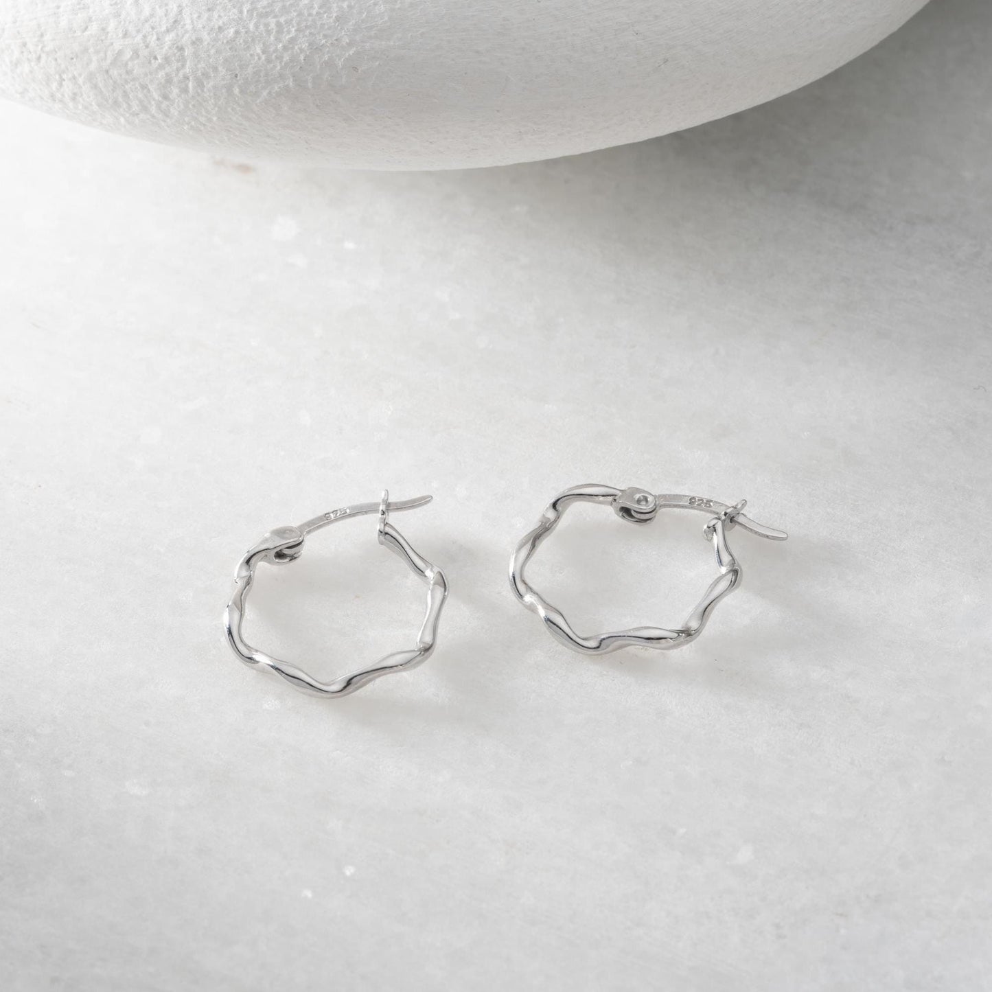 Wave hoop earrings crafted from 925 sterling silver with 14K gold plating option, displayed on a marble background.
