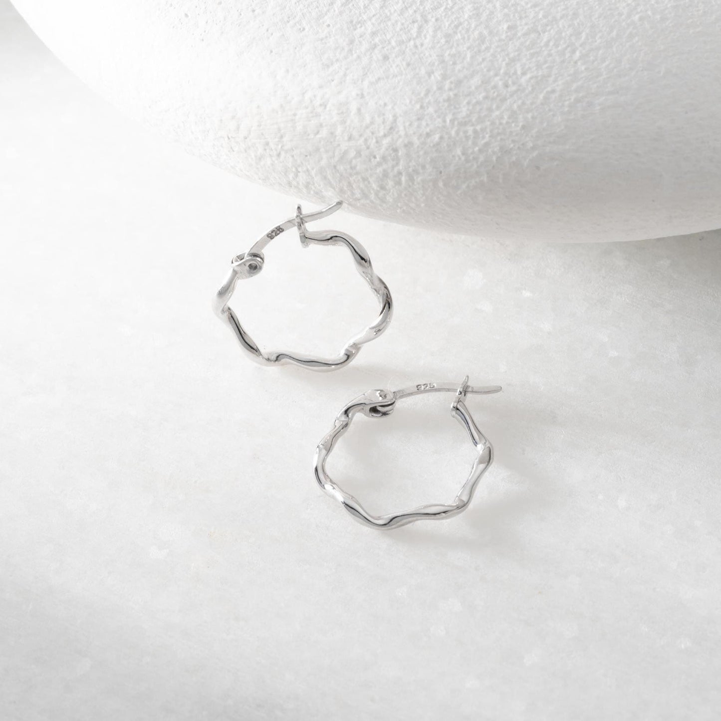 Wave hoop earrings crafted from 925 sterling silver with 14K gold plating option, displayed on a marble background.