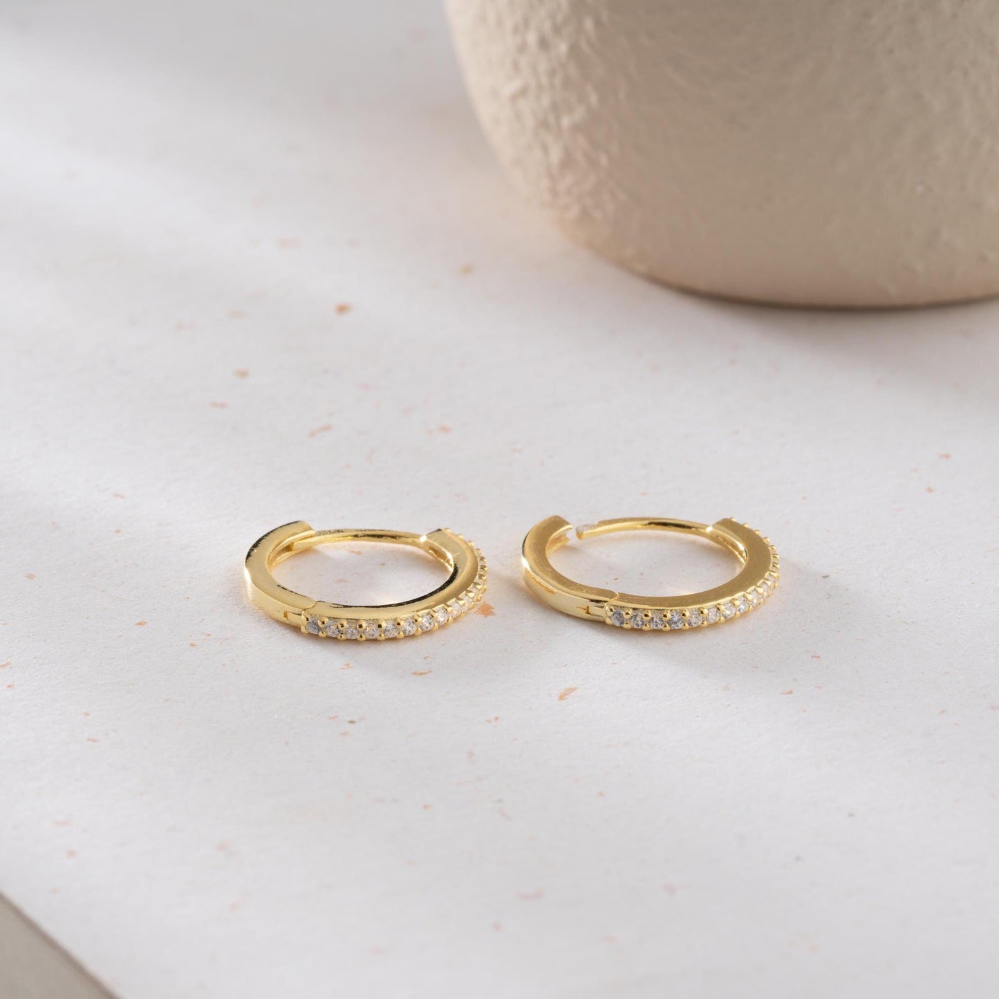 Minimalist hoop earrings with cubic zirconia stones in 925 sterling silver and 14K gold plated options, displayed on a neutral background.