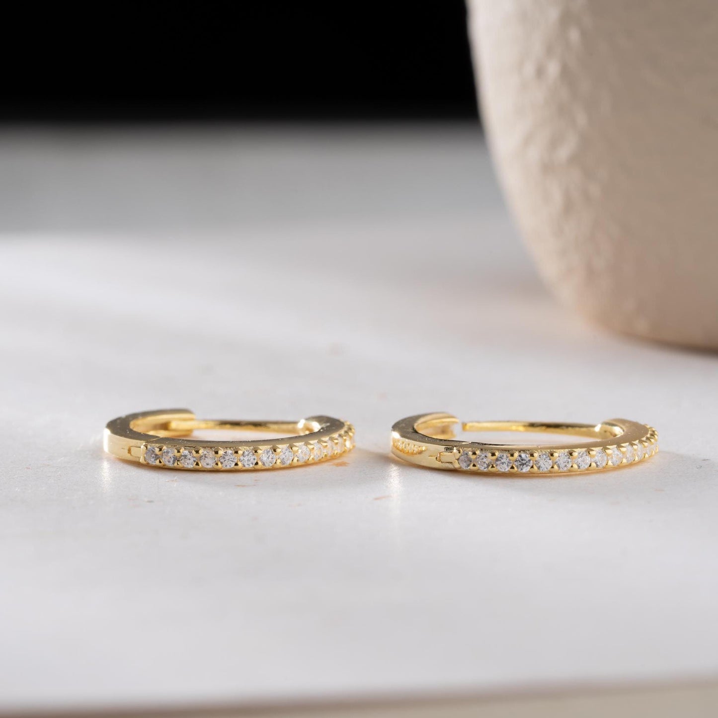 Minimalist hoop earrings with cubic zirconia stones in 925 sterling silver and 14K gold plated options, displayed on a neutral background.