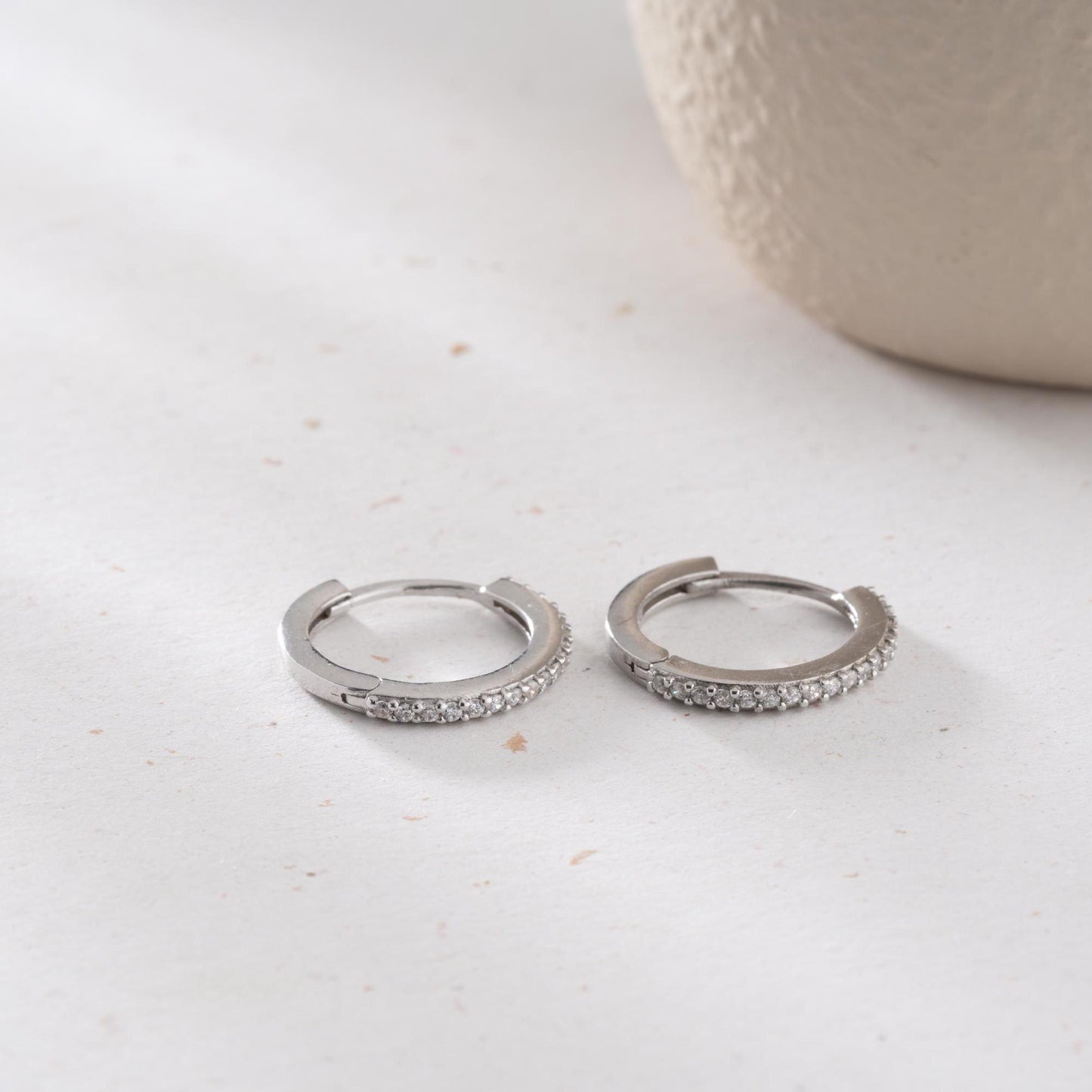 Minimalist hoop earrings with cubic zirconia stones in 925 sterling silver and 14K gold plated options, displayed on a neutral background.