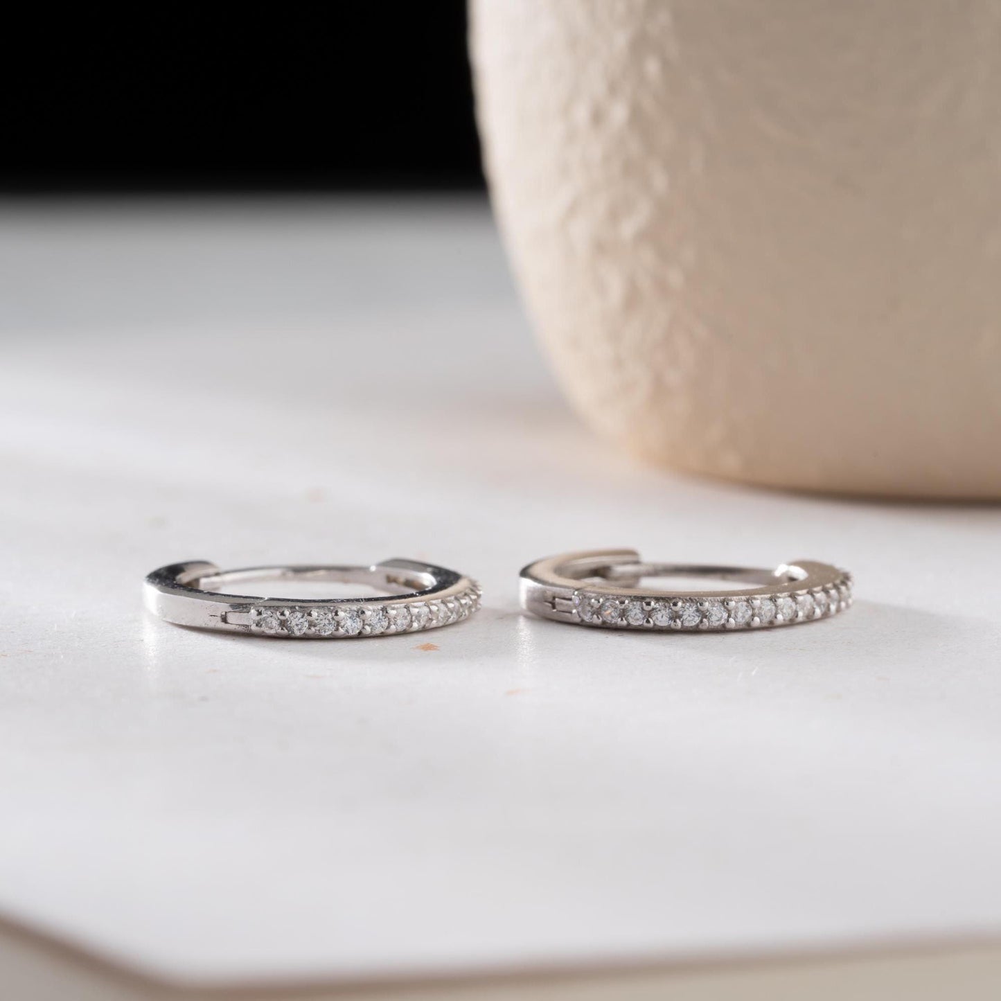 Minimalist hoop earrings with cubic zirconia stones in 925 sterling silver and 14K gold plated options, displayed on a neutral background.