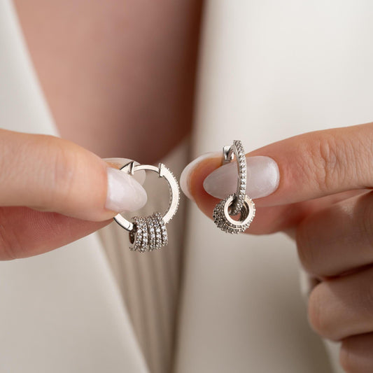 Multi-ring hoop earrings with sparkling cubic zirconia stones in 925 sterling silver and 14K gold-plated options, displayed on a marble background.