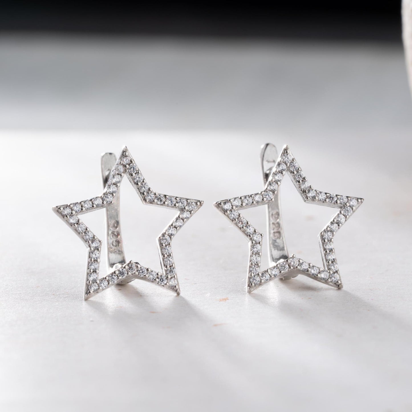 Star-shaped earrings with cubic zirconia stones, available in 925 sterling silver and 14K gold plated options, displayed on a minimalist background.