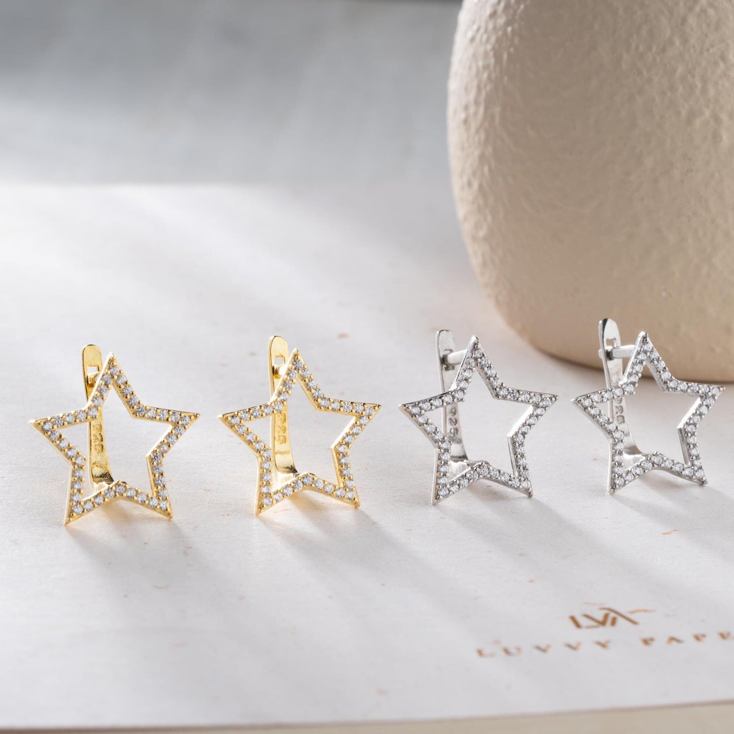 Star-shaped earrings with cubic zirconia stones, available in 925 sterling silver and 14K gold plated options, displayed on a minimalist background.
