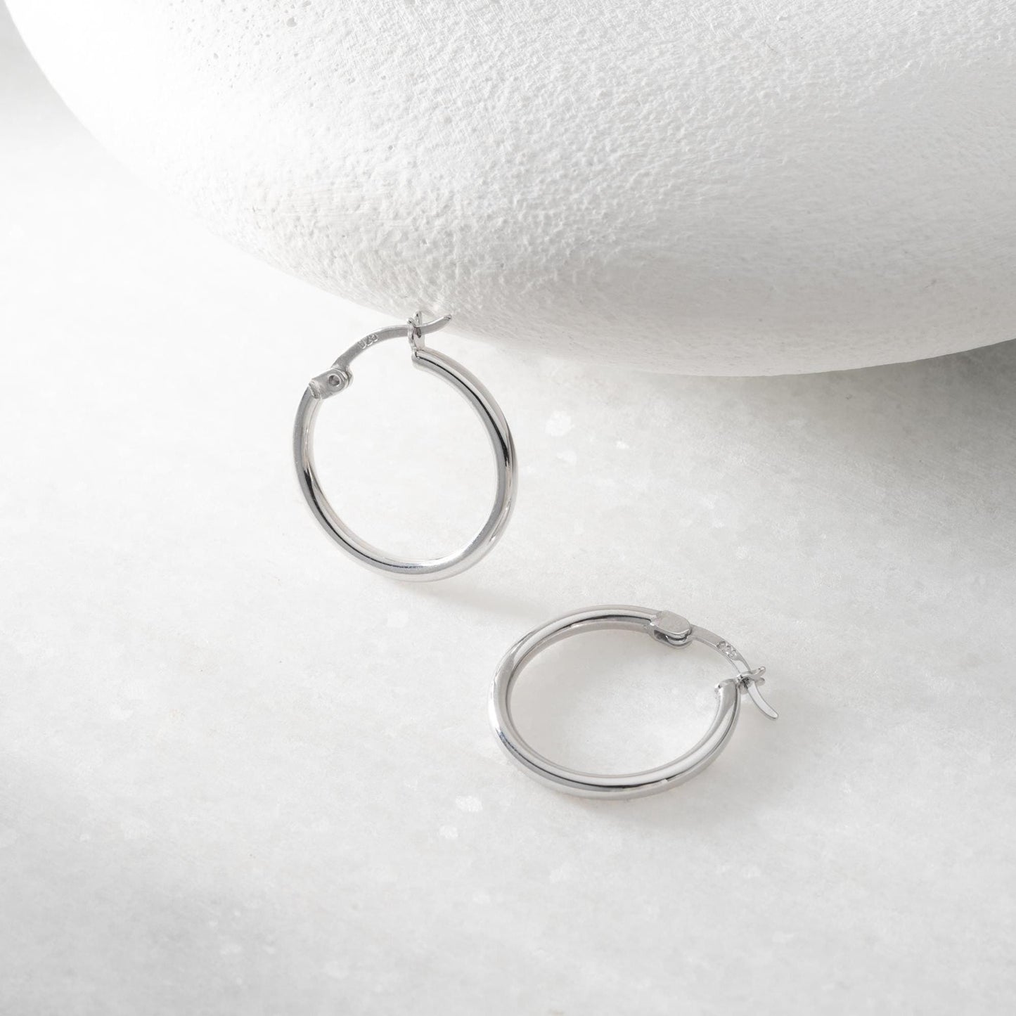classic hoop earrings in 925 sterling silver and 14K gold plated options, featuring a minimalist polished design displayed on a marble background