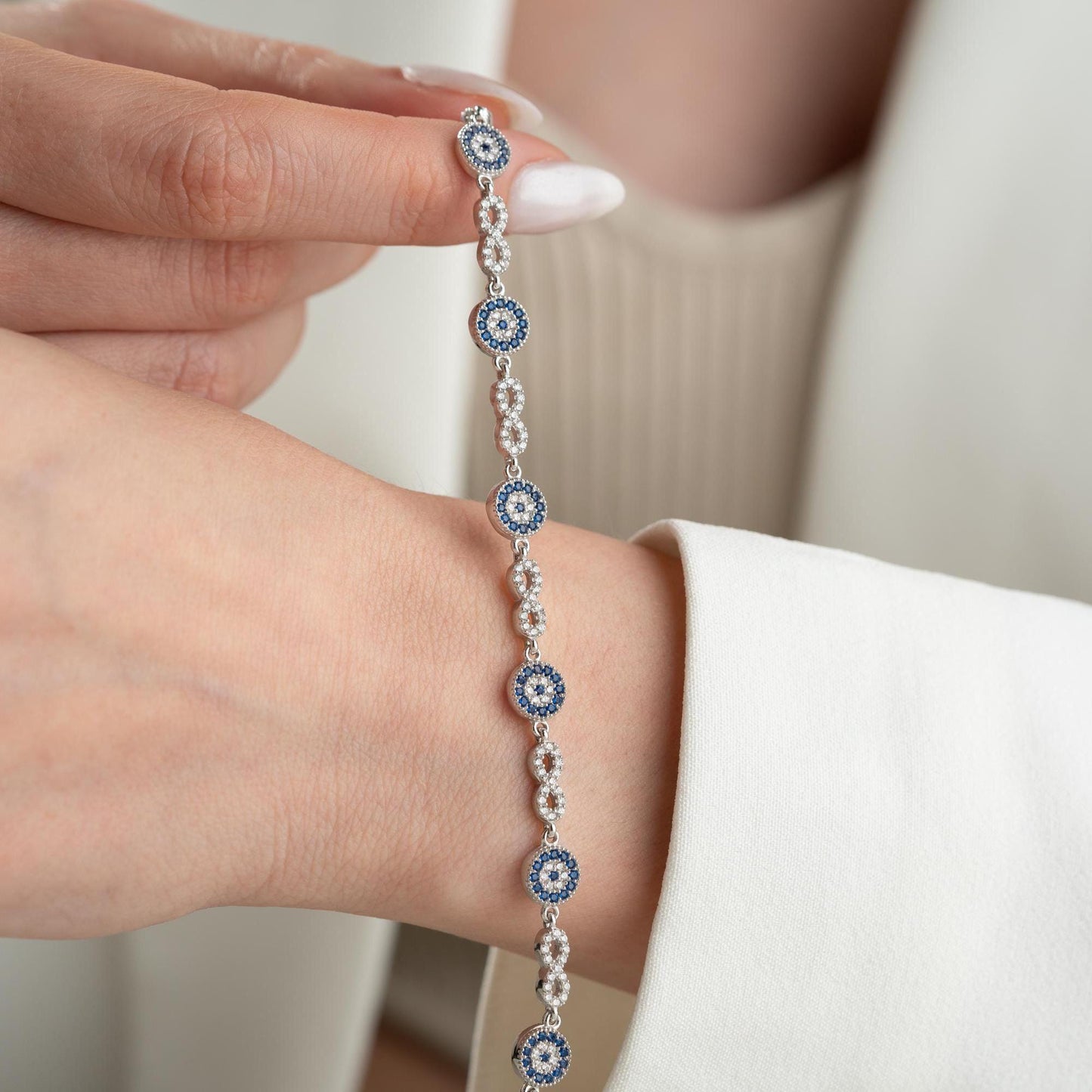Infinity Evil Eye Bracelet with 925 Sterling Silver and 14K Gold Plated options, featuring blue evil eye accents, photographed in gold and silver variations.