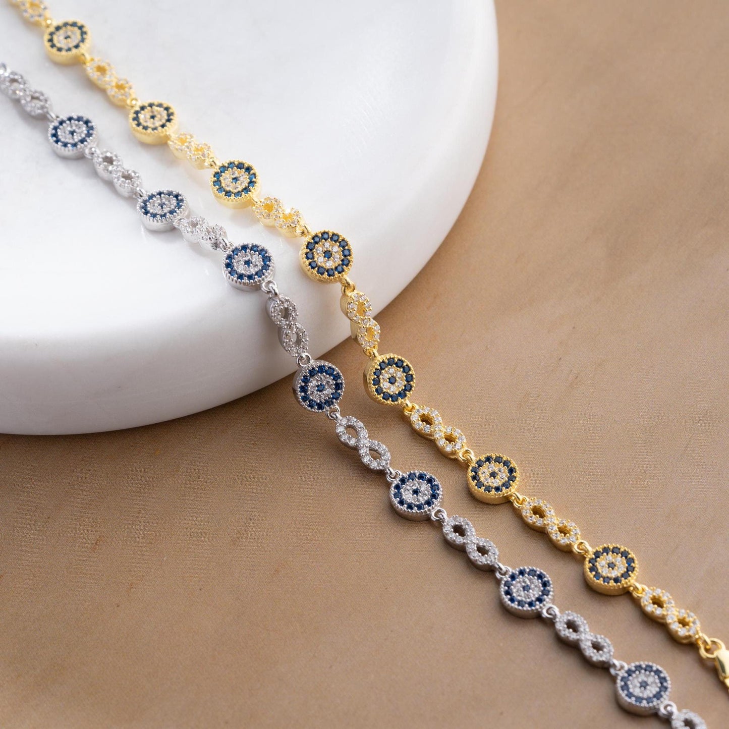 Infinity Evil Eye Bracelet with 925 Sterling Silver and 14K Gold Plated options, featuring blue evil eye accents, photographed in gold and silver variations.