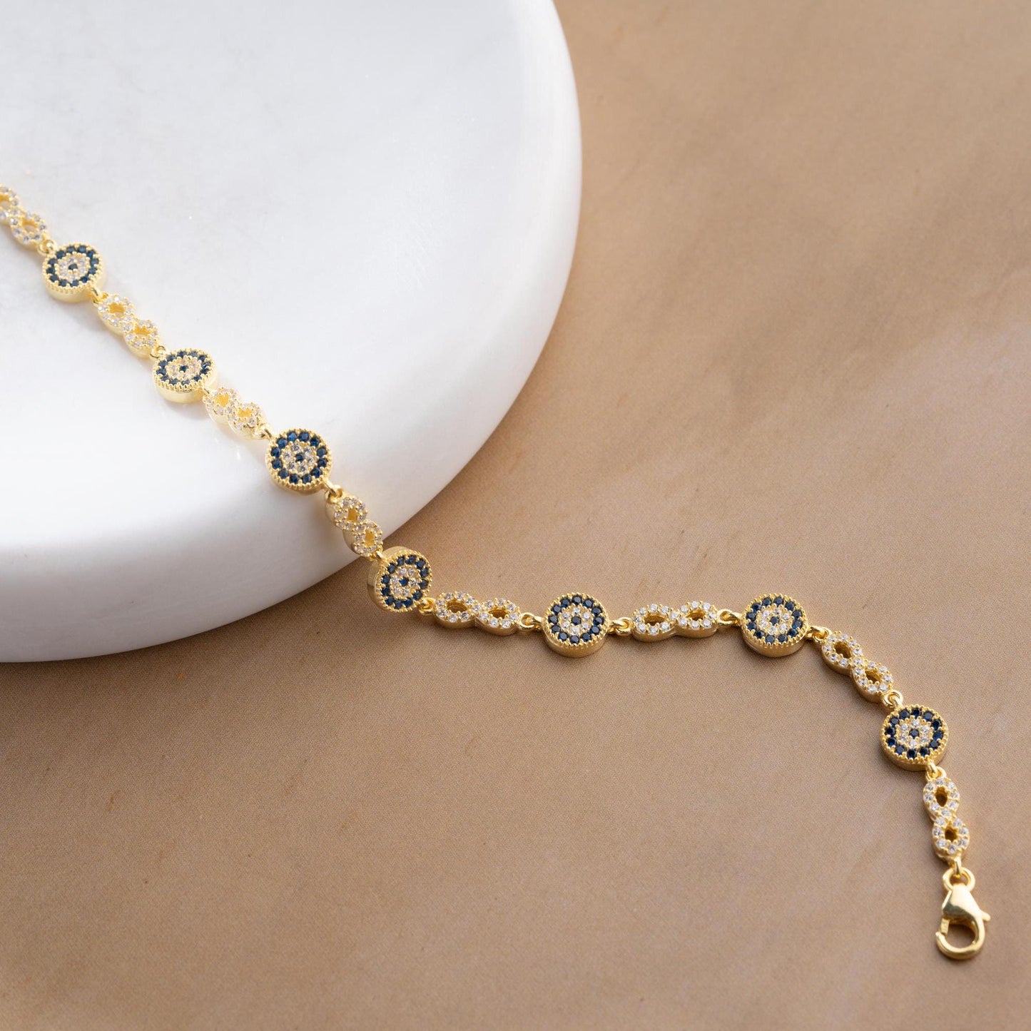 Infinity Evil Eye Bracelet with 925 Sterling Silver and 14K Gold Plated options, featuring blue evil eye accents, photographed in gold and silver variations.