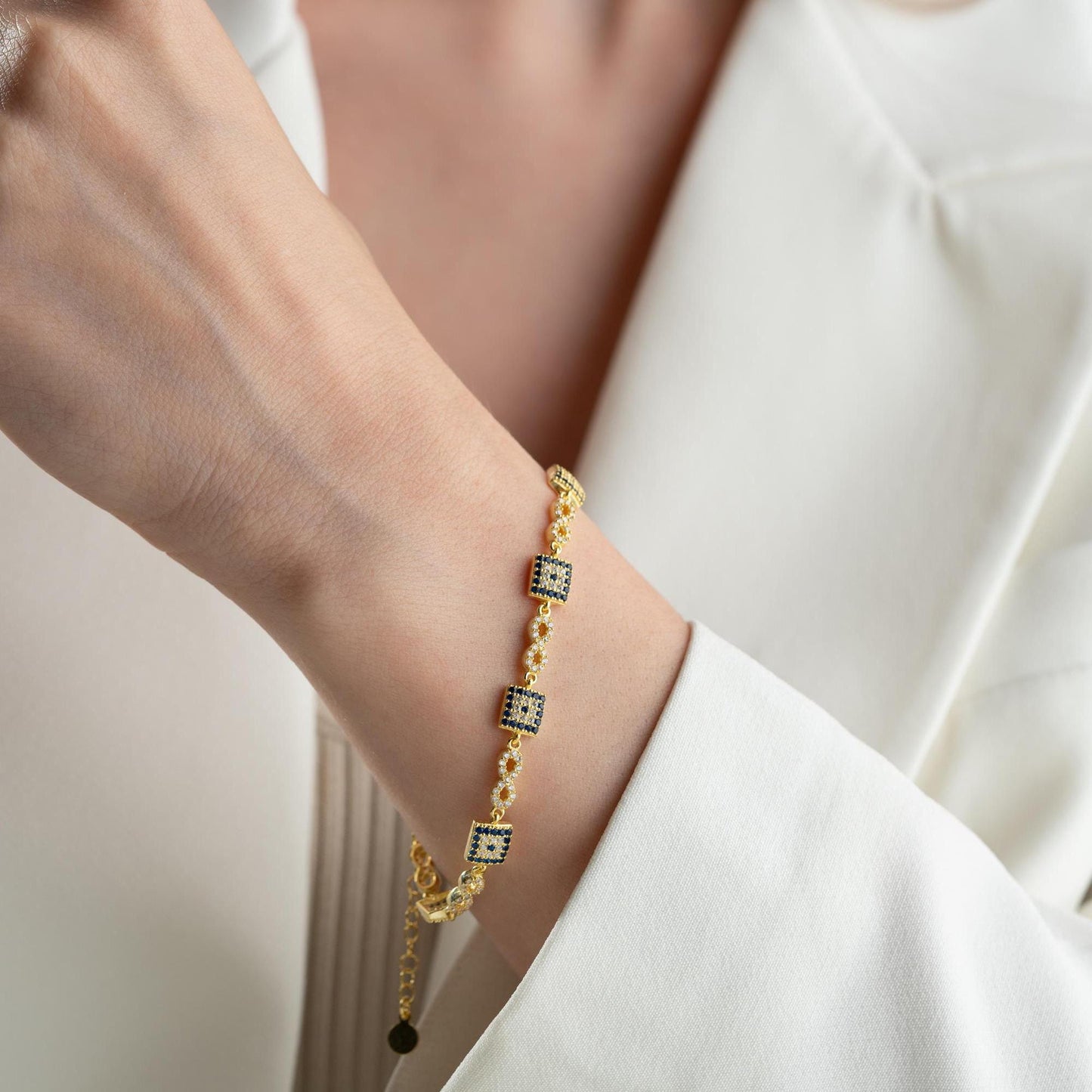 Elegant charm bracelet featuring square evil eye motifs and infinity symbols, crafted in 925 Sterling Silver with cubic zirconia stones, available in silver and gold finishes, perfect for festive gifting.