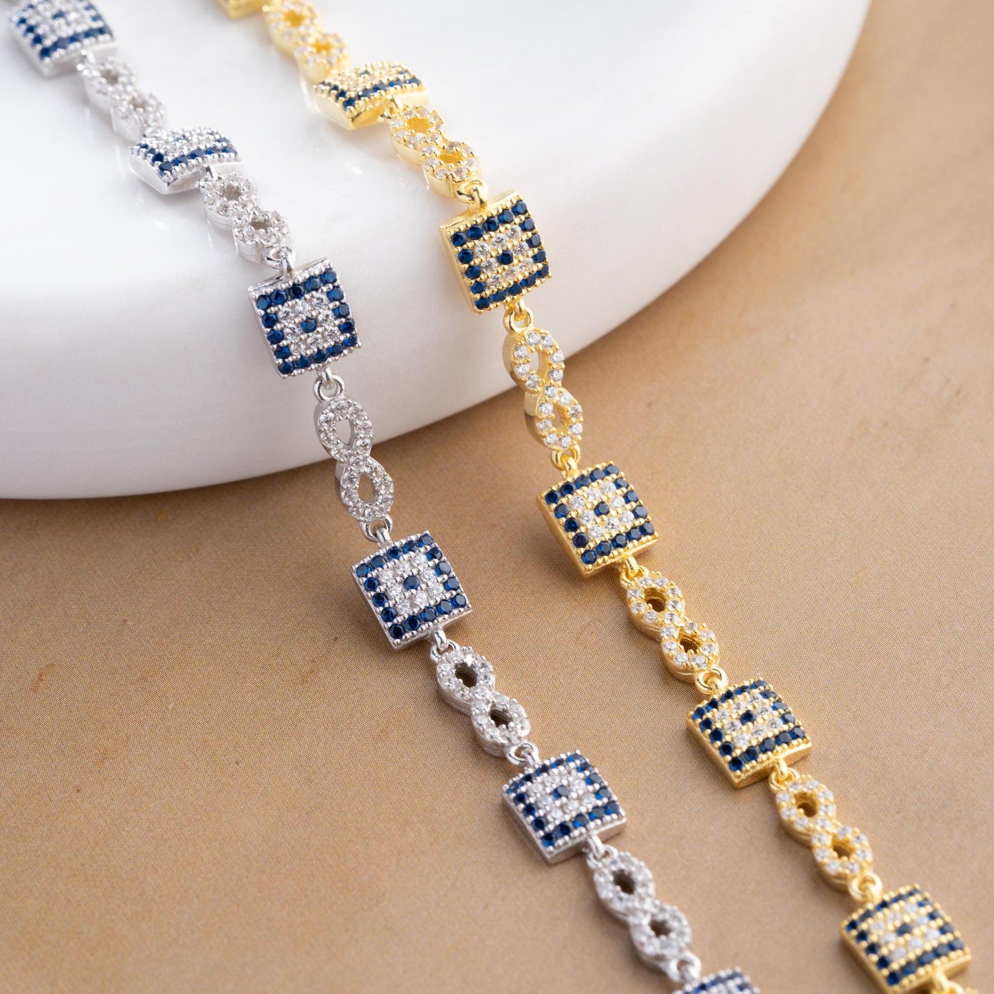 Elegant charm bracelet featuring square evil eye motifs and infinity symbols, crafted in 925 Sterling Silver with cubic zirconia stones, available in silver and gold finishes, perfect for festive gifting.